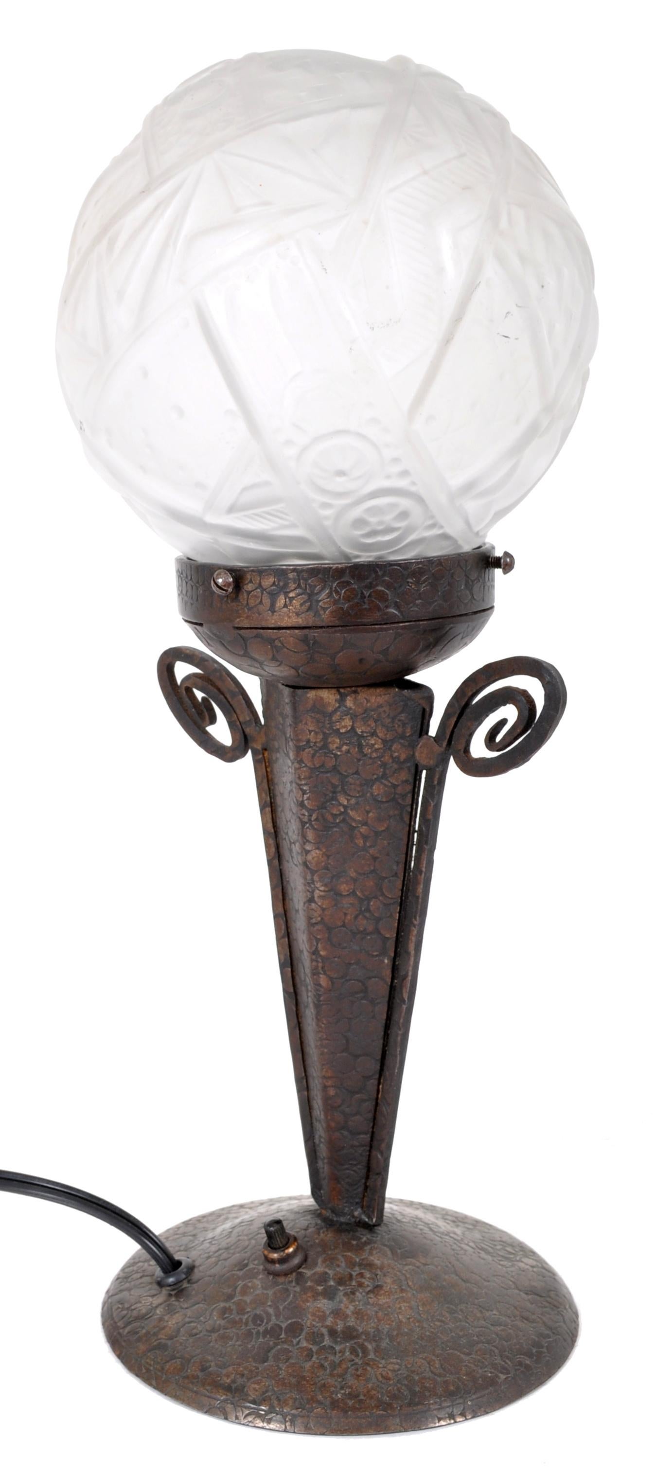 Une bonne lampe de table ancienne de style Art Déco français, attribuée à Edgar Brandt et à l'abat-jour en verre à la manière de Daum, vers 1920. La base de la lampe est en fer raboté à la main. La lampe a un abat-jour sphérique en verre dépoli et