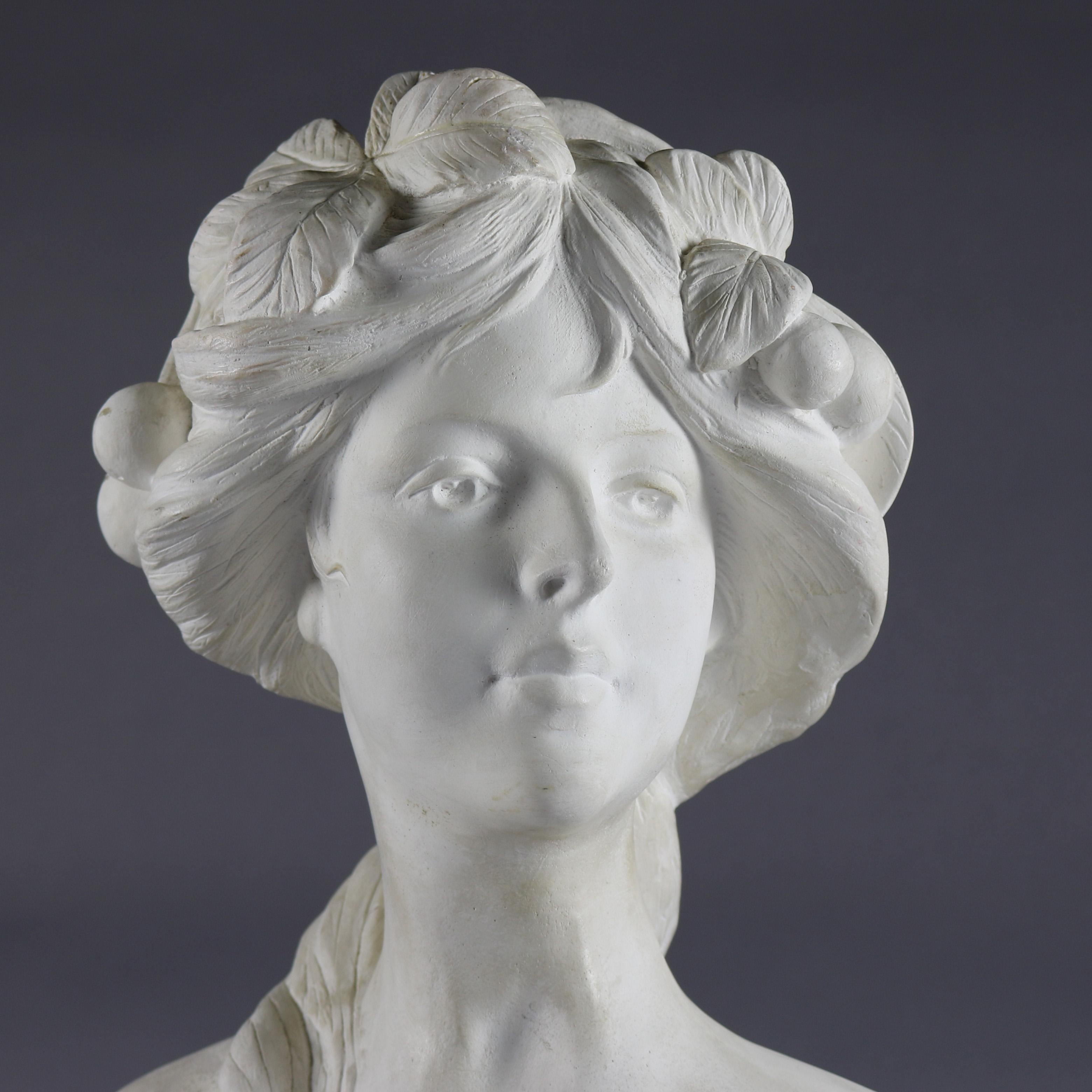 An antique French Art Nouveau chalkware portrait bust features bust of woman with long hair and crown of plum branch, seated on faceted plinth, circa 1920.

Measures: 19.5