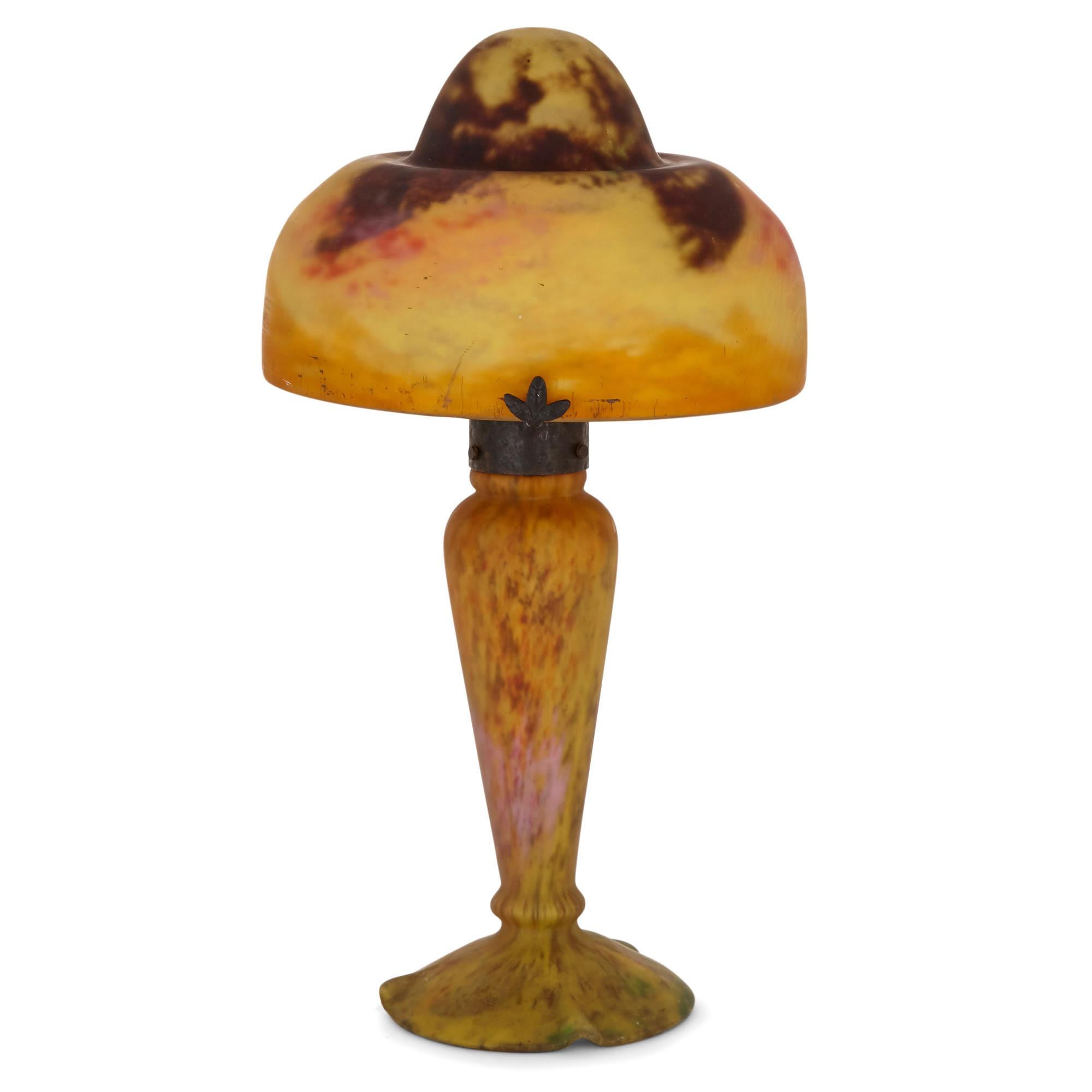 This exquisite Art Nouveau lamp is by the celebrated French glasswork studio Daum which was founded in 1878 in Nancy, France. The lamp is inscribed ‘DAUM, NANCY’. 

The lamp is of mushroom shape. Its glass shade is composed of a small pointed dome