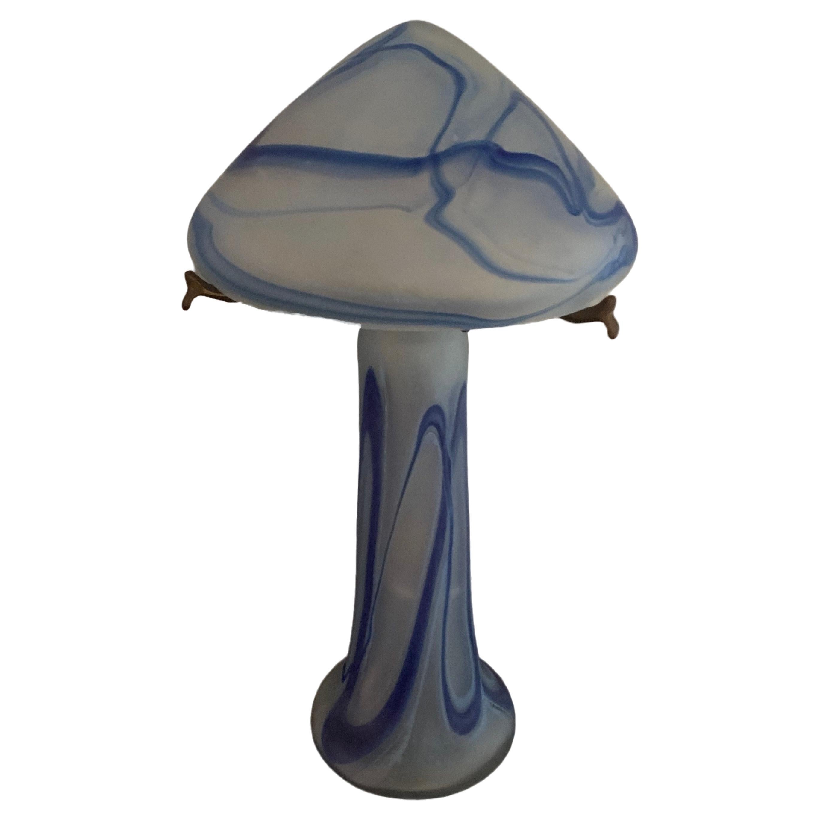 Exquise lampe Art Nouveau fabriquée en France. 

Forme traditionnelle de champignon avec un dôme pointu. La base en verre et les deux pièces sont reliées par une tige en laiton qui s'attache à la base. 

Verre bleu, blanc et transparent. 

Vers les