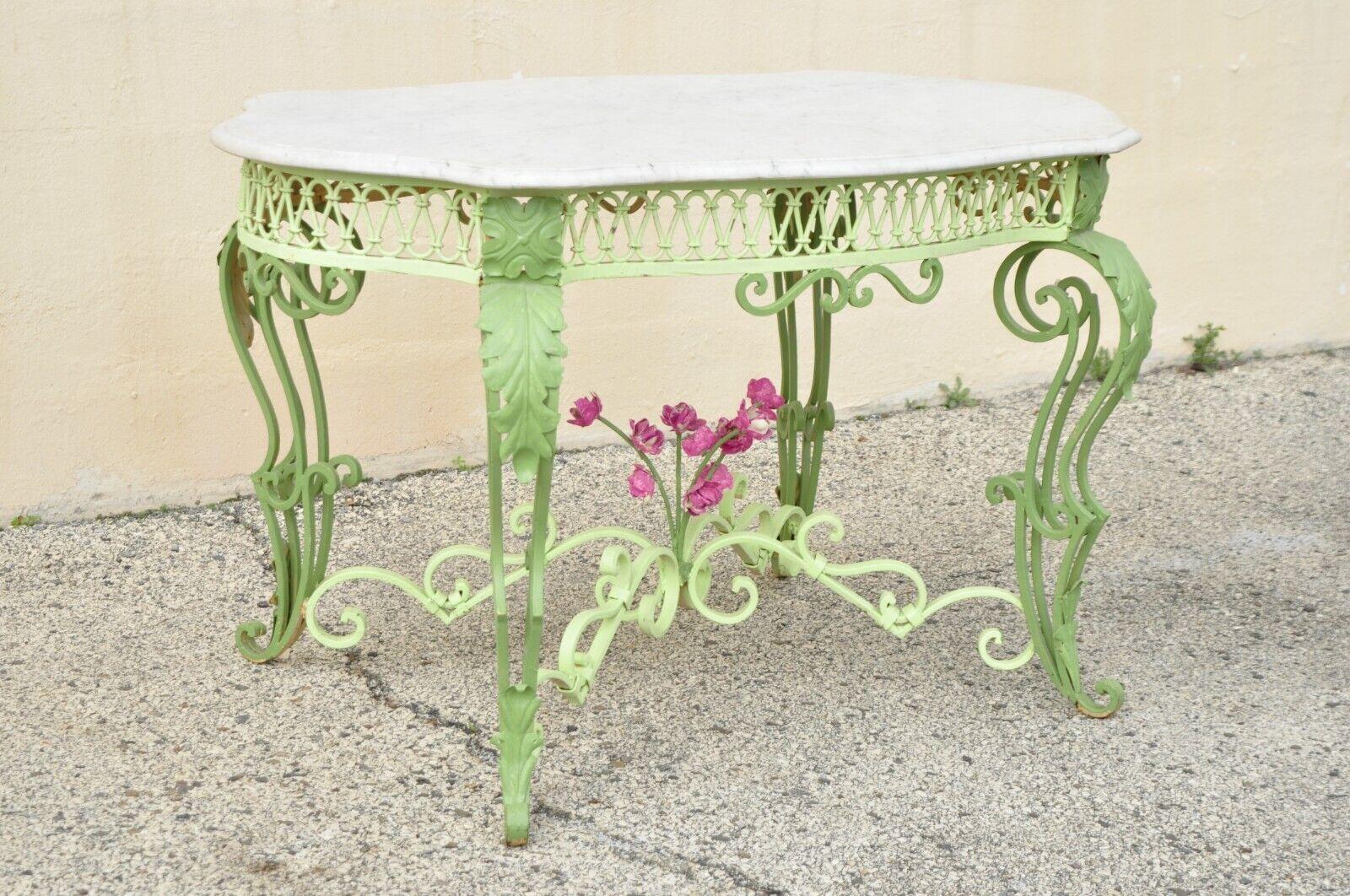 Ancienne table console centrale en fer forgé et marbre. L'objet présente une base en fer forgé ornée, un support de brancard, un bouquet de fleurs roses au centre, des pieds à volutes, un plateau de tortue en marbre blanc, une finition peinte en