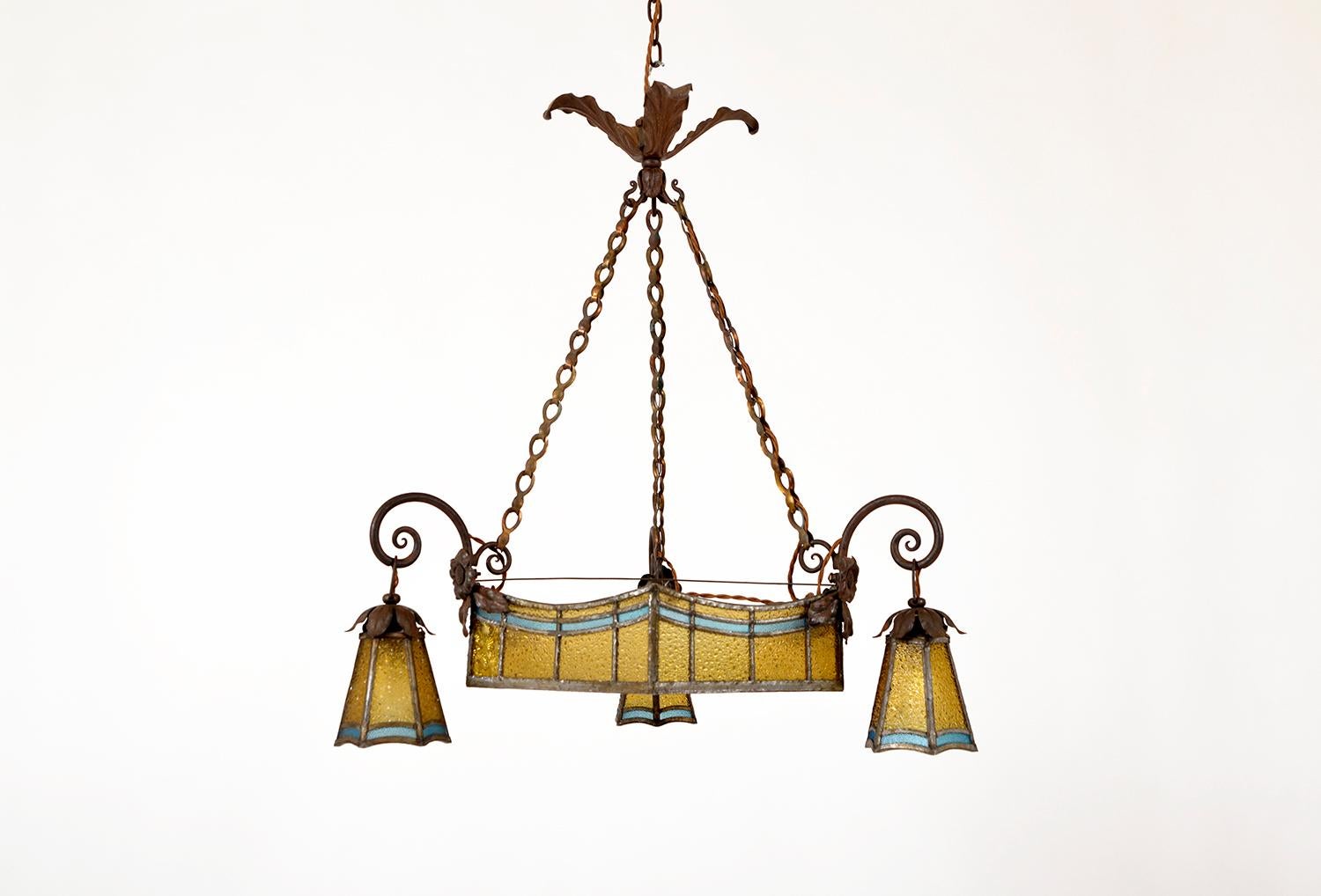 This stunning and very elegant leaded glass pendant light dating from the early 20th century looks like it has come straight out of a Parisian café.
The piece has been lavished with the most intricate of forged ironwork; hung from an ornate acanthus