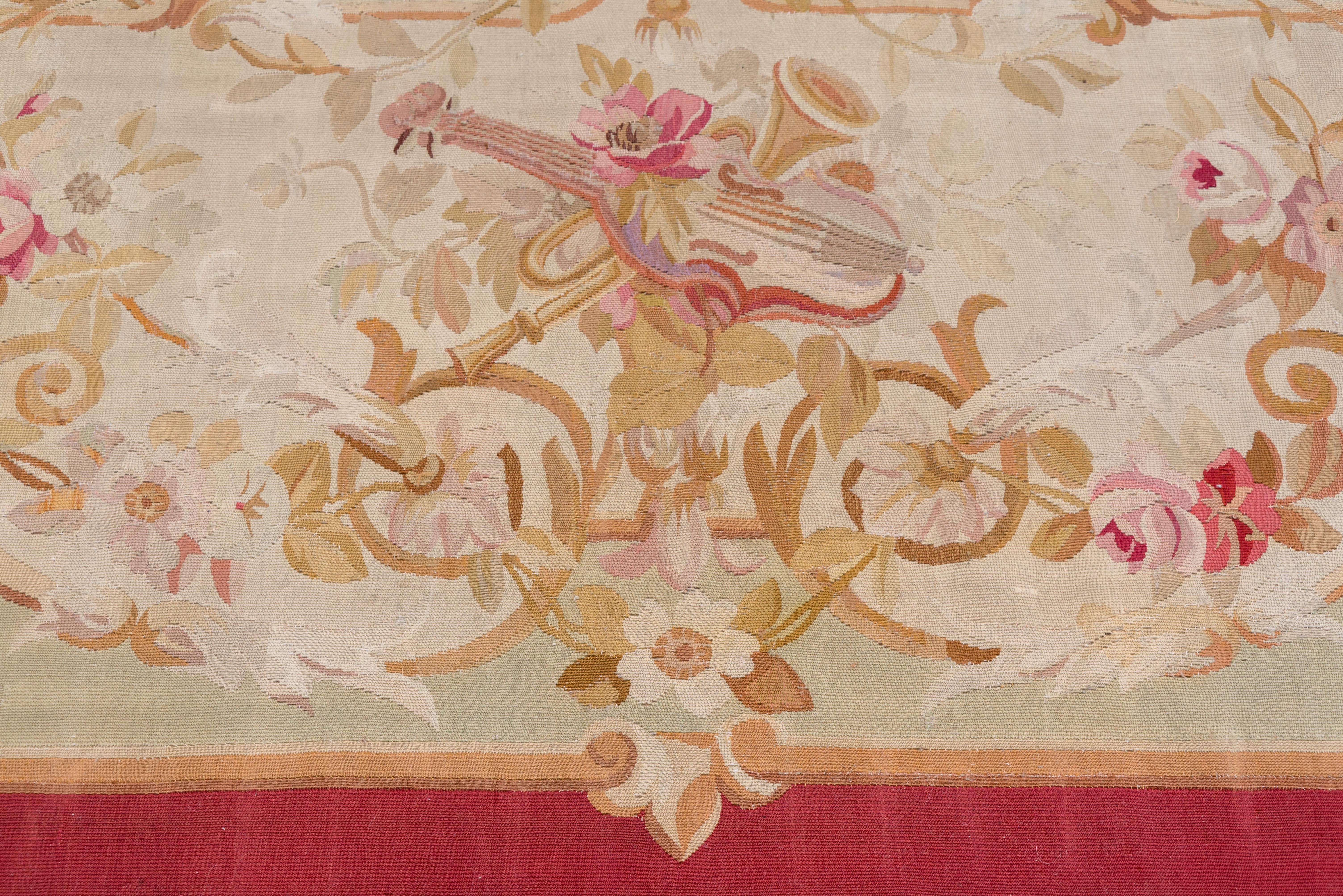 This French tapestry-weave pile less carpet shows a pinched, oval cartouche ecru medallion with a central bouquet, on a flower accented beige field. The corner-shaped plain brown border frames the whole.