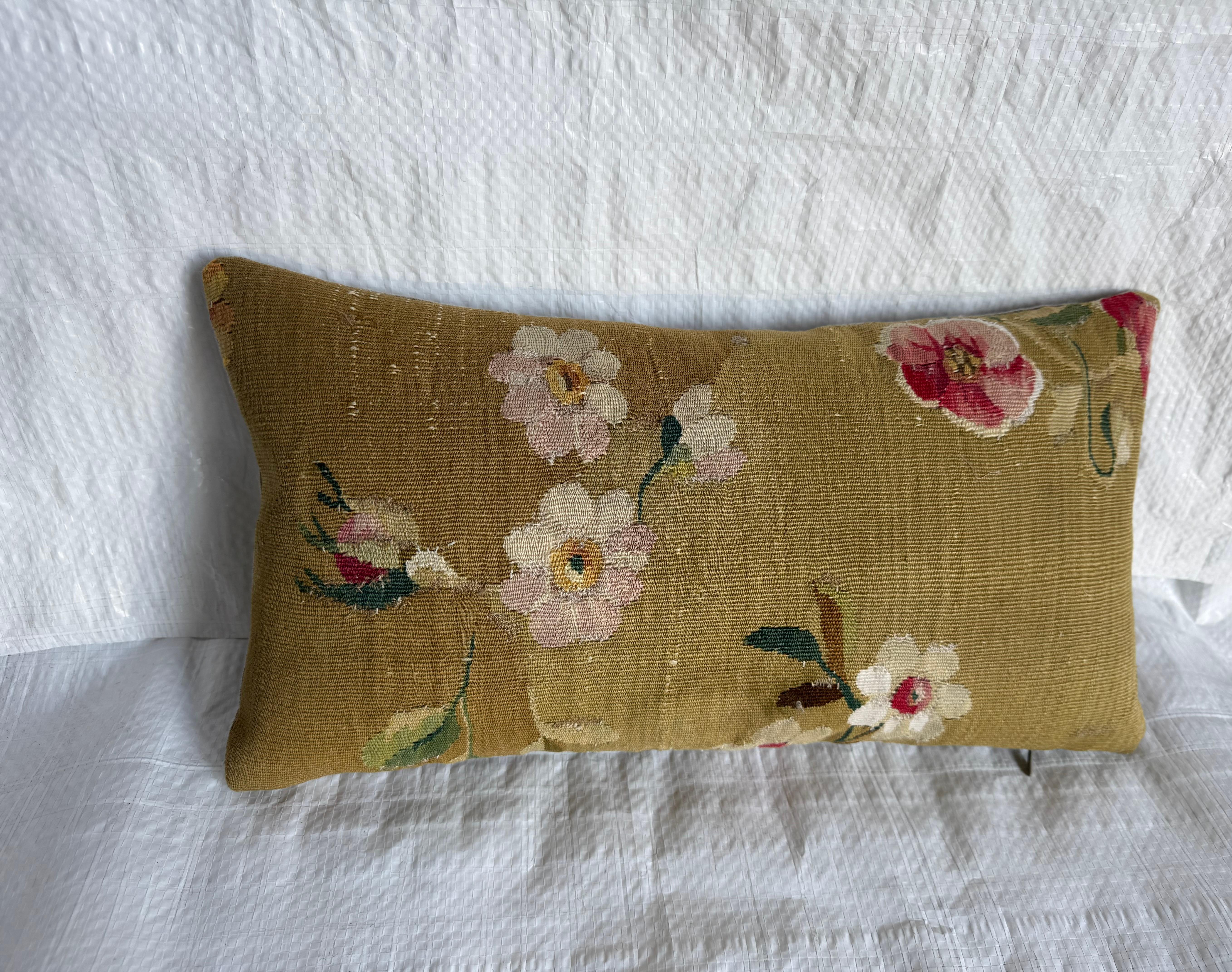 Magnifique coussin en tapisserie d'Aubusson du milieu du XIXe siècle, tissé de doux motifs floraux dans des tons de rose blush, de crème, de rose et de vert. Le fond est un ton chaud d'or olive typique des textiles anciens d'Aubusson de l'époque et