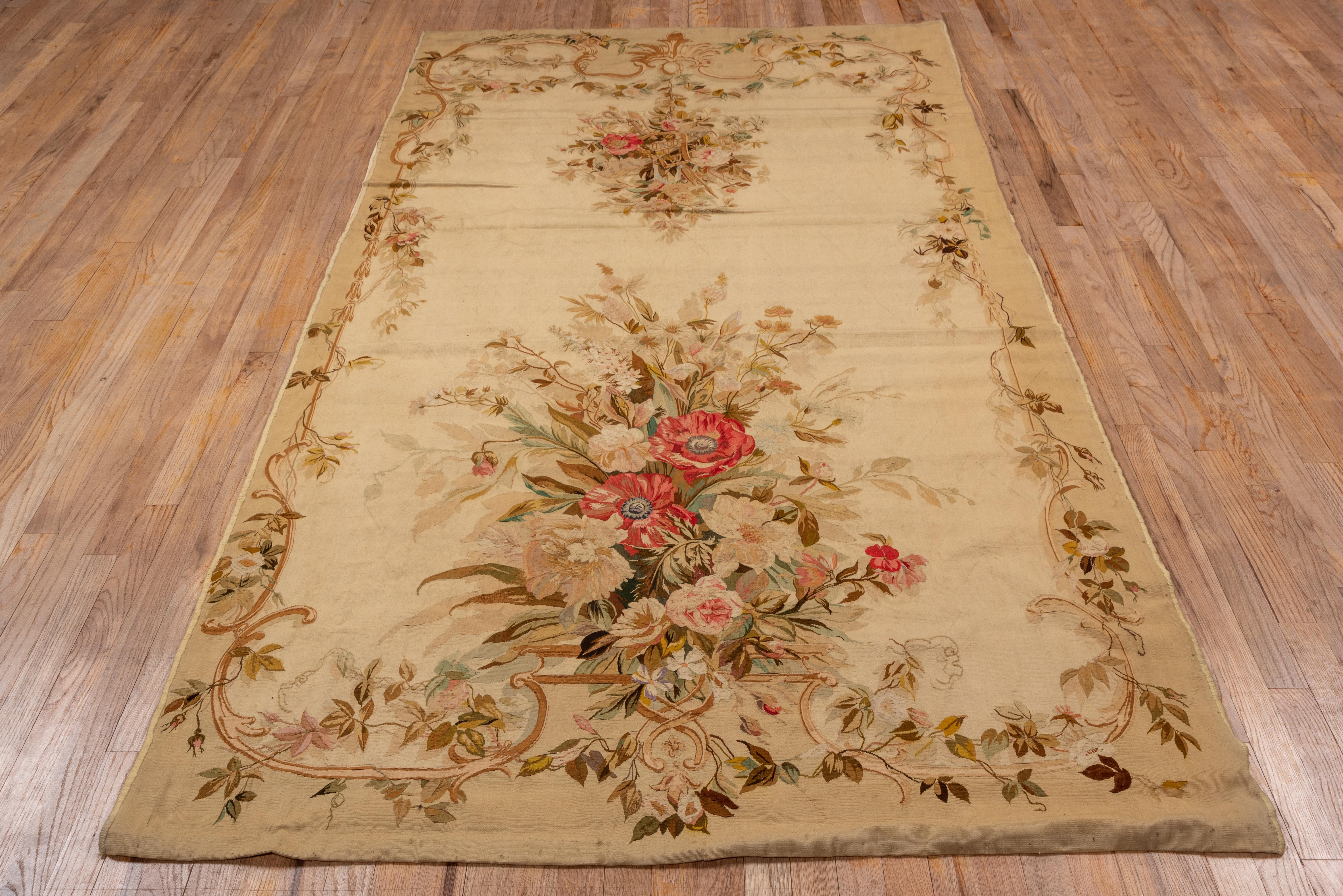 In a rare size, this tapestry-woven French antique could be used on the floor or as a wall hanging. The ivory field shows a hanging bouquet amid swags at one end and a larger rose bush at the opposite end. Narrow partial staves in the side borders.