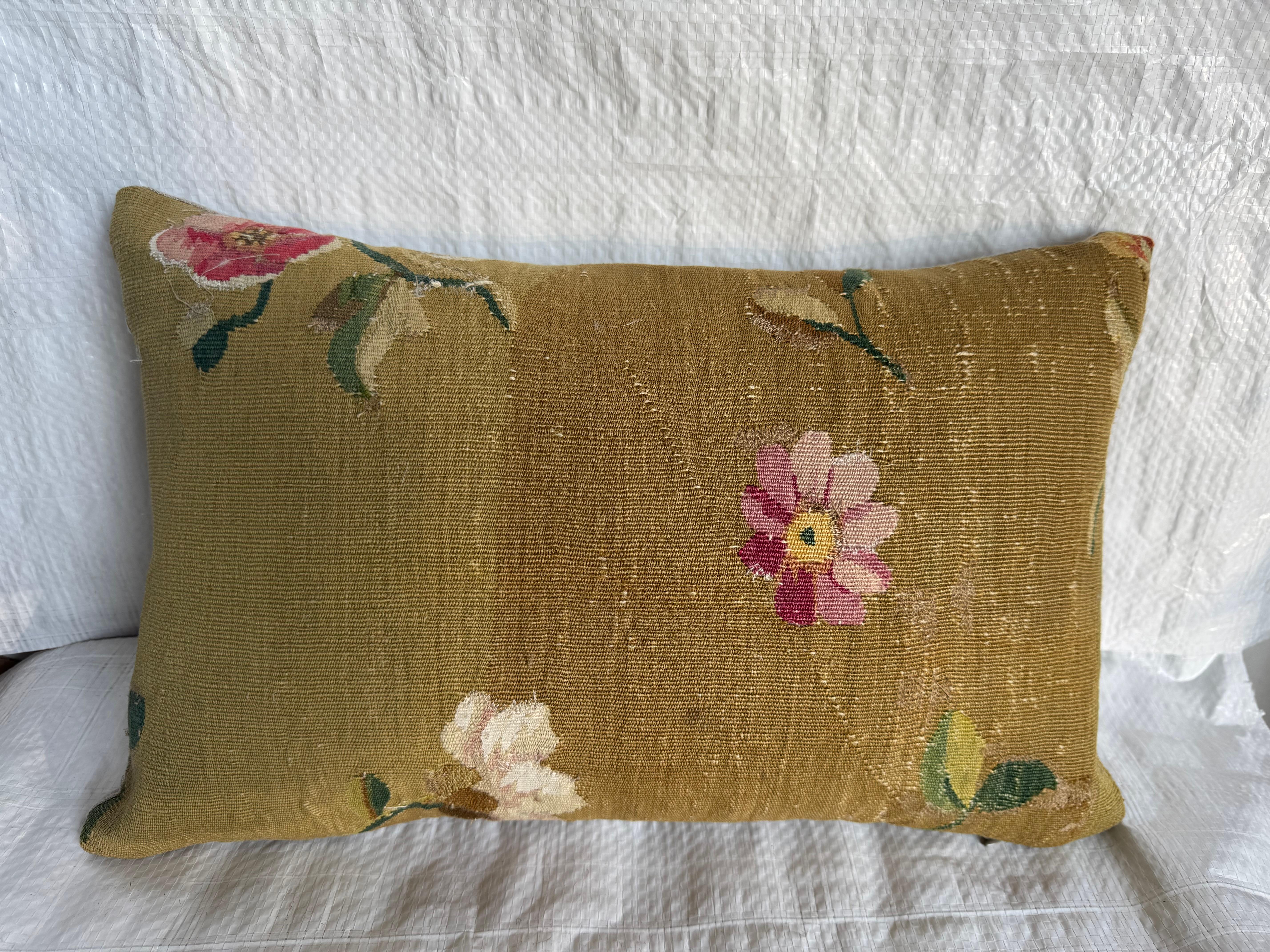 Un bellissimo cuscino francese ad arazzo Aubusson del 1850 con morbidi motivi floreali nei toni del rosa, del crema e del verde su uno sfondo caldo. L'arazzo è tessuto a mano con le delicate irregolarità e la sottile patina che solo i veri tessuti