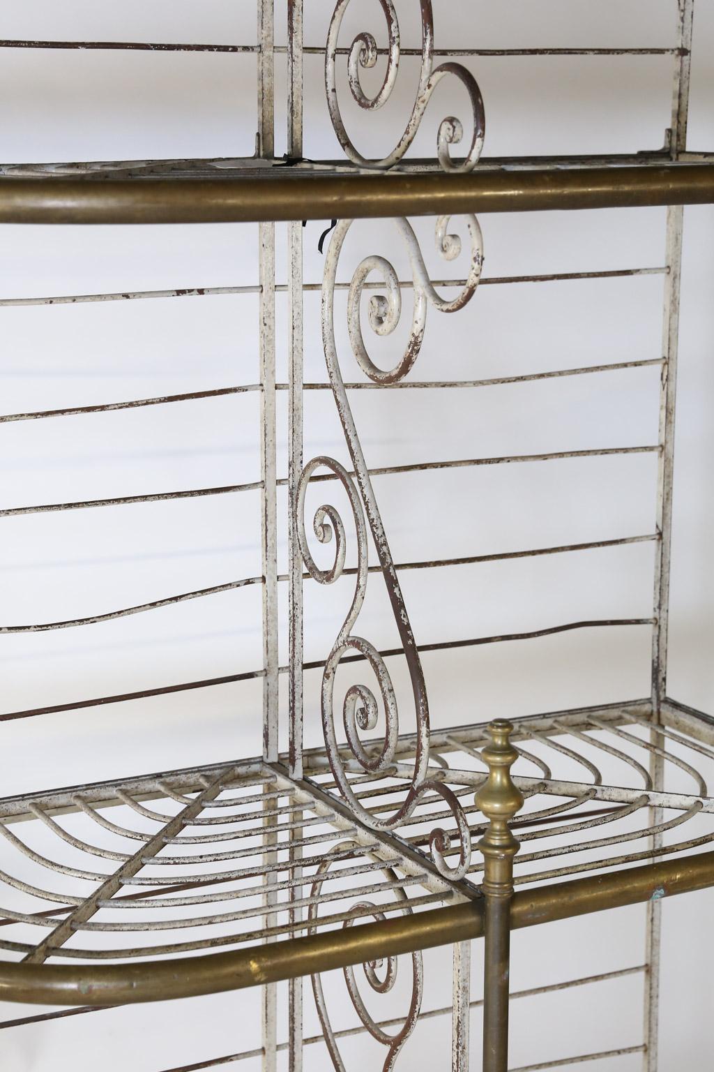Found in France, this beautiful antique bakers rack is made with iron and brass. Perfect in scale and size for any home, this piece offers three tiers divided by scroll work through the middle of each tier offering six divided spaces. The piece