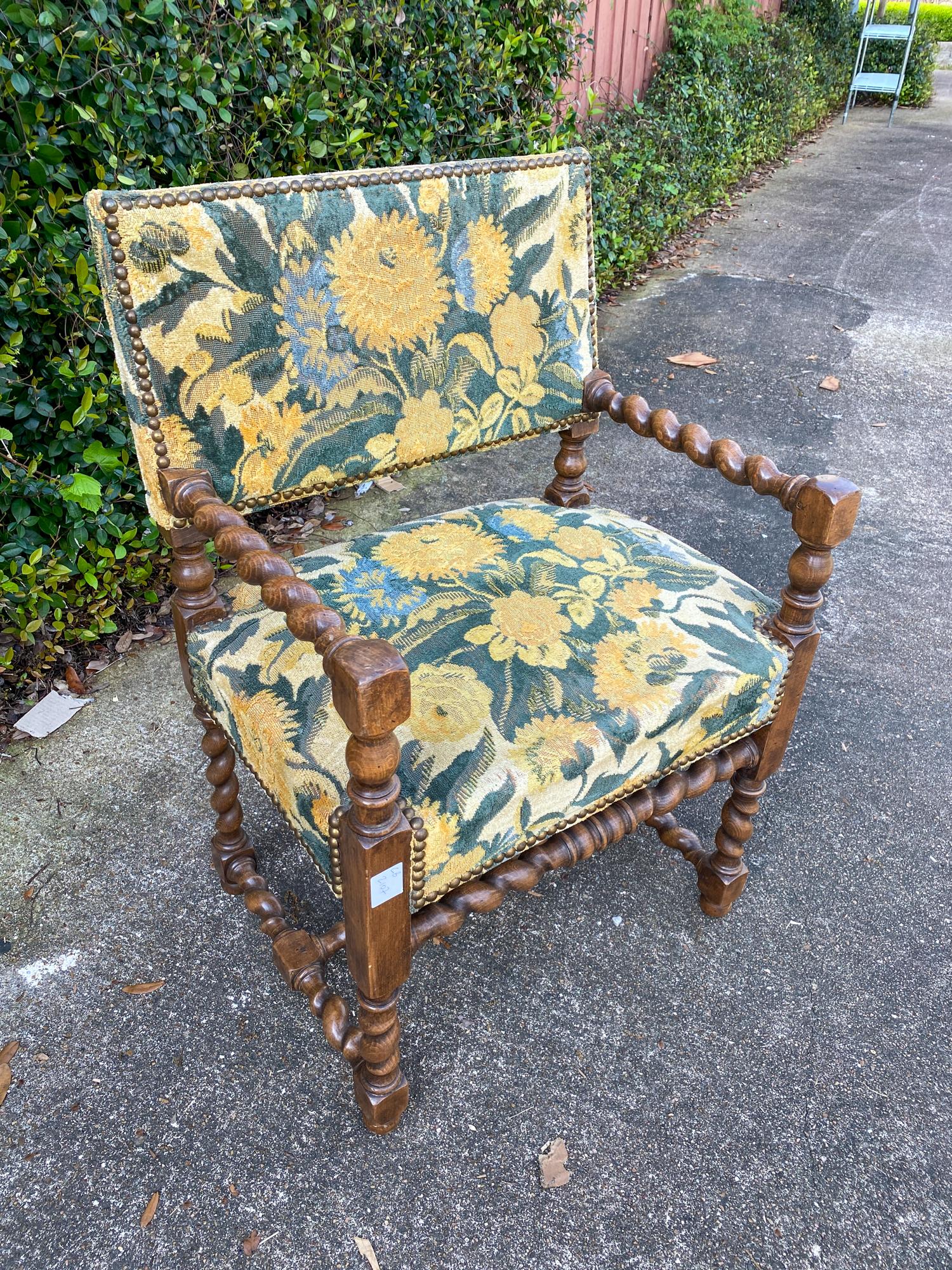 This is an antique French barley-twist armchair with floral upholstery and brass nail head accents. The barley twist style is present on the arms and legs, carved in French oak, with original finish. Made around the turn of the 20th century, circa