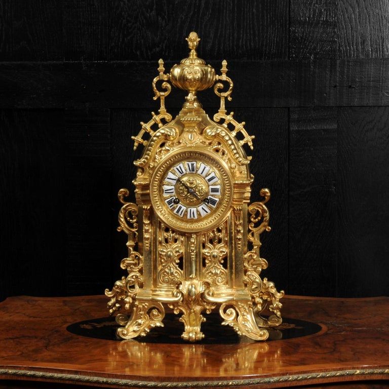 A beautiful original antique French clock, Baroque in style and well modelled in gilt bronze. Profusely decorated with scrolls and foliage, acanthus bracket feet, and featuring a fretted front to allow a glimpse of the pendulum gently swinging