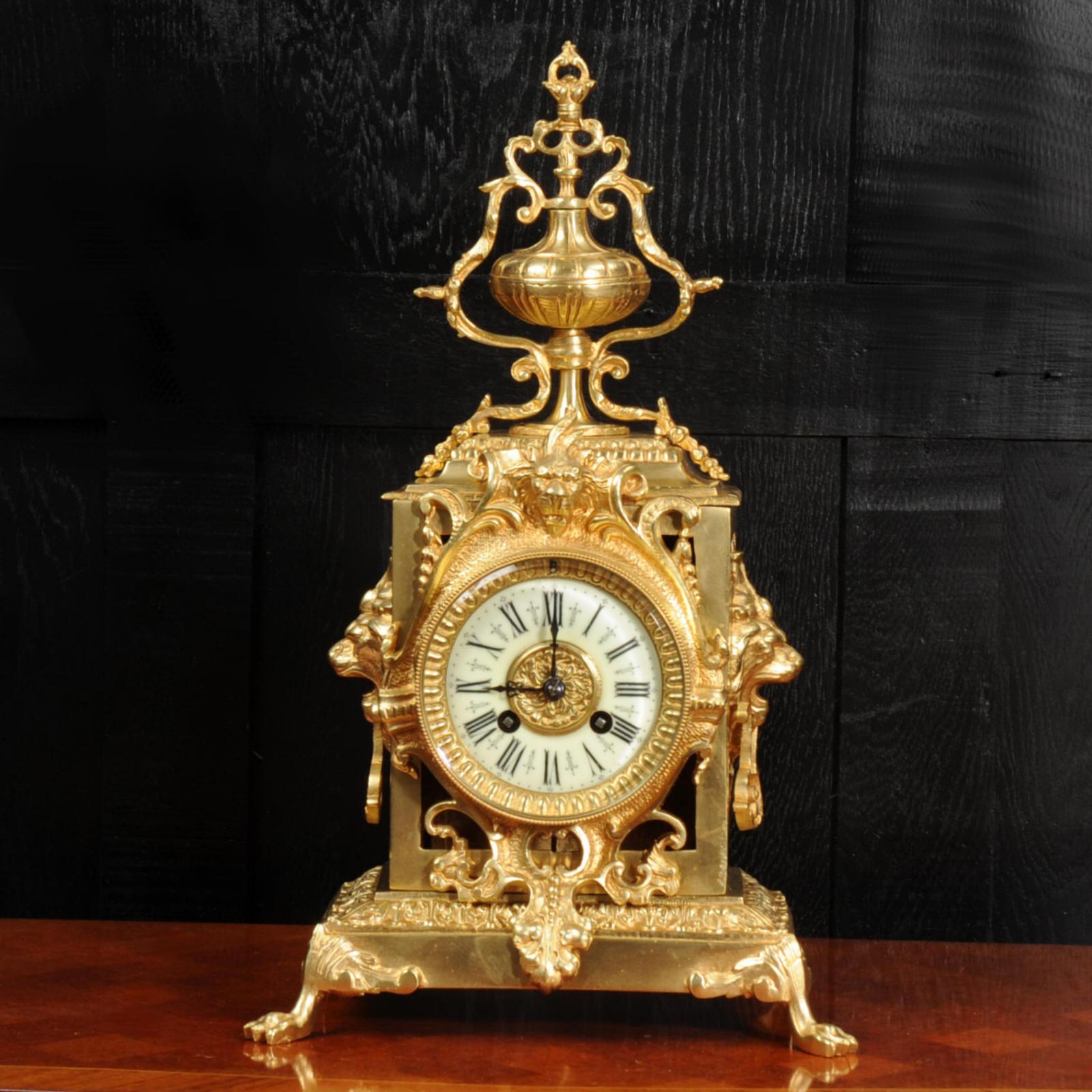A stunning antique French Baroque clock. It is beautifully made in gilt bronze and features large lions masks to the sides and it sits on hairy paw feet. The front is pieced to allow a glimpse of the pendulum gently swinging within the case.

The
