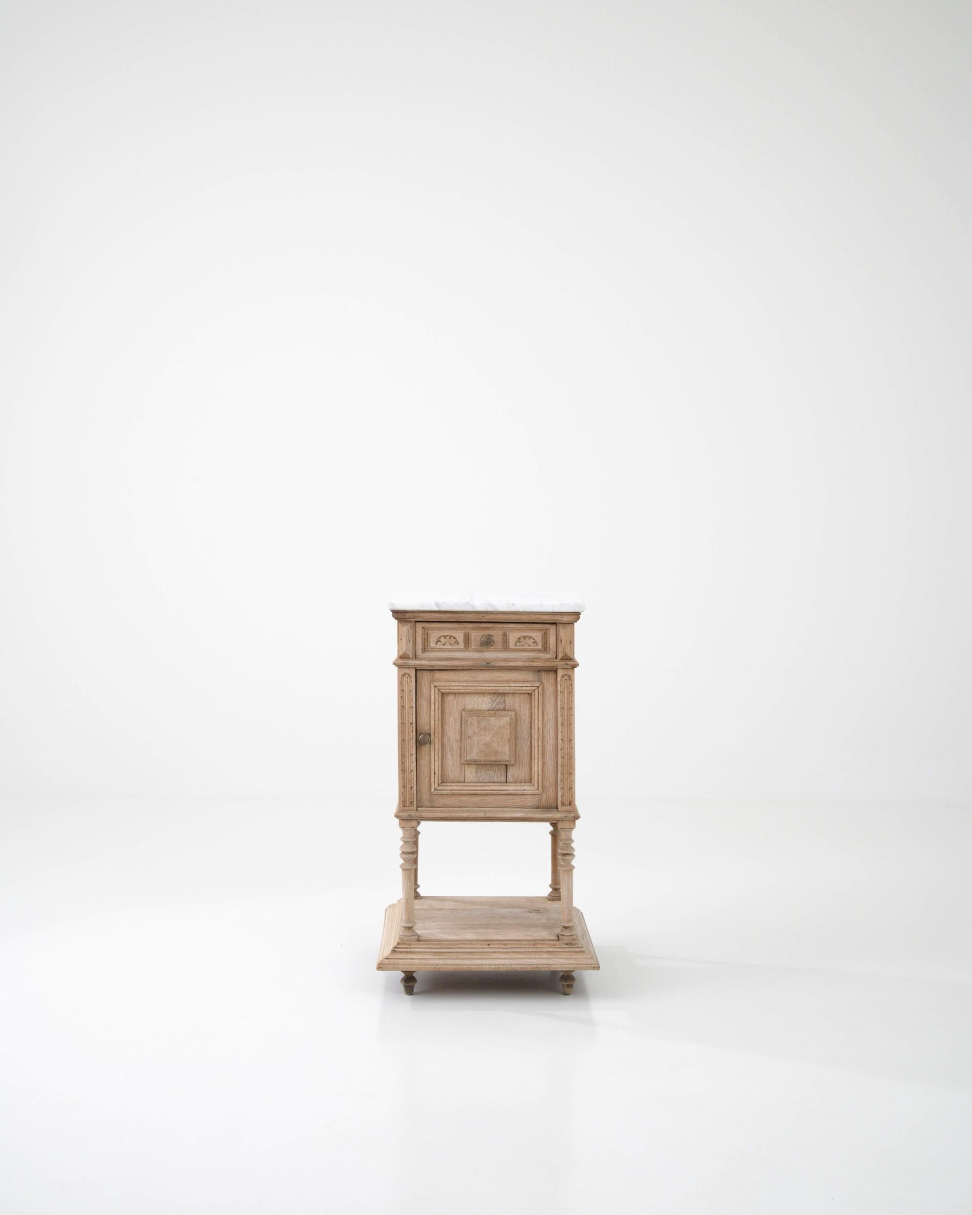 Ein Nachttisch aus Eiche, hergestellt in Frankreich um 1900. Dieser traditionell gefertigte Nachttisch ist mit einer Marmorplatte verziert, die ein Gefühl von Ruhe und raffinierter Eleganz ausstrahlt. Wolkengraue Adern ziehen sich durch die