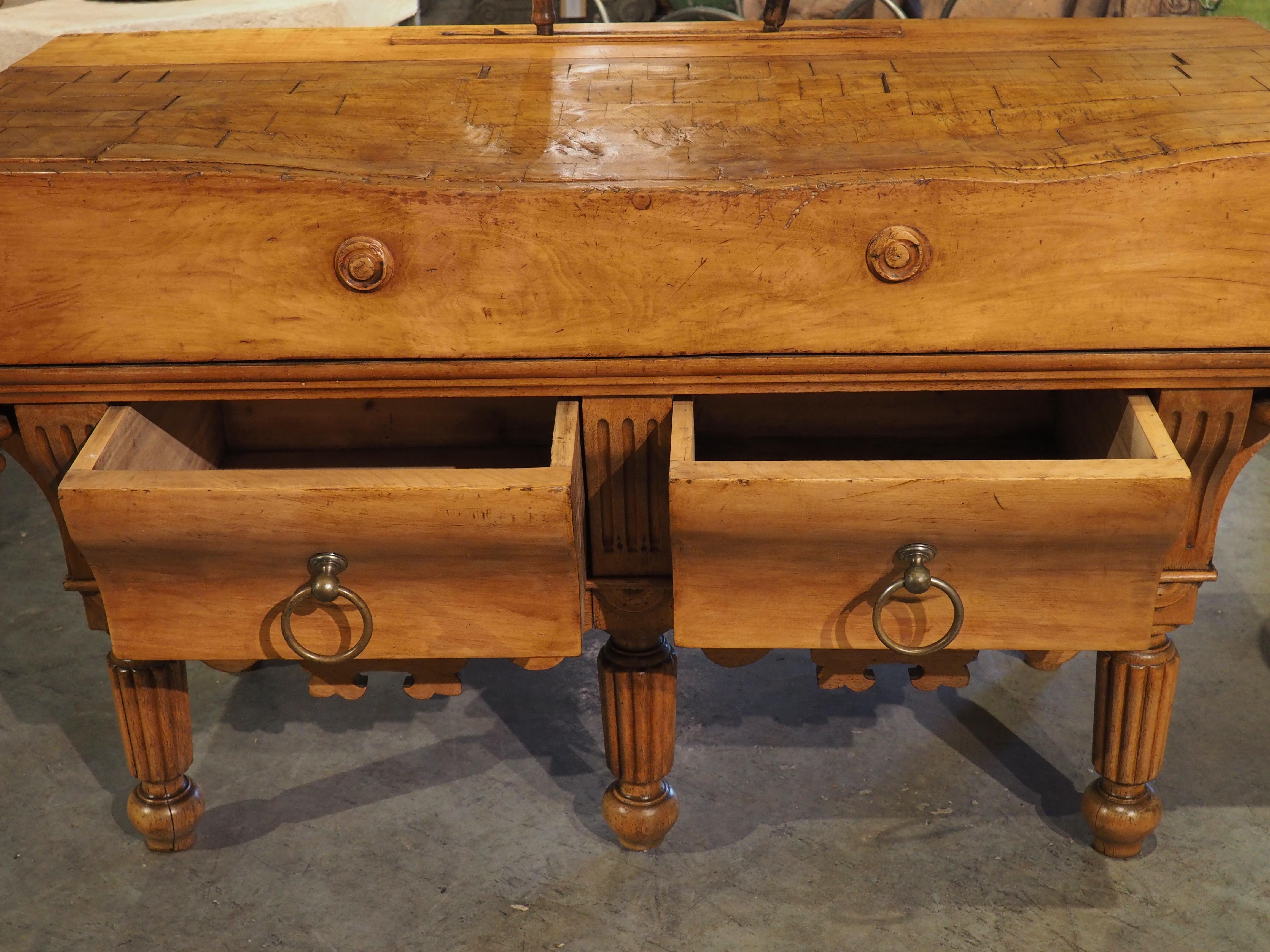 Hand carved from beechwood, this large butcher block most likely was used in a French boucherie around 1880. Shaped from decades of use (also included are two antique butcher knives, one monogramed “K.B.”, that slot into a raised slot in the back),