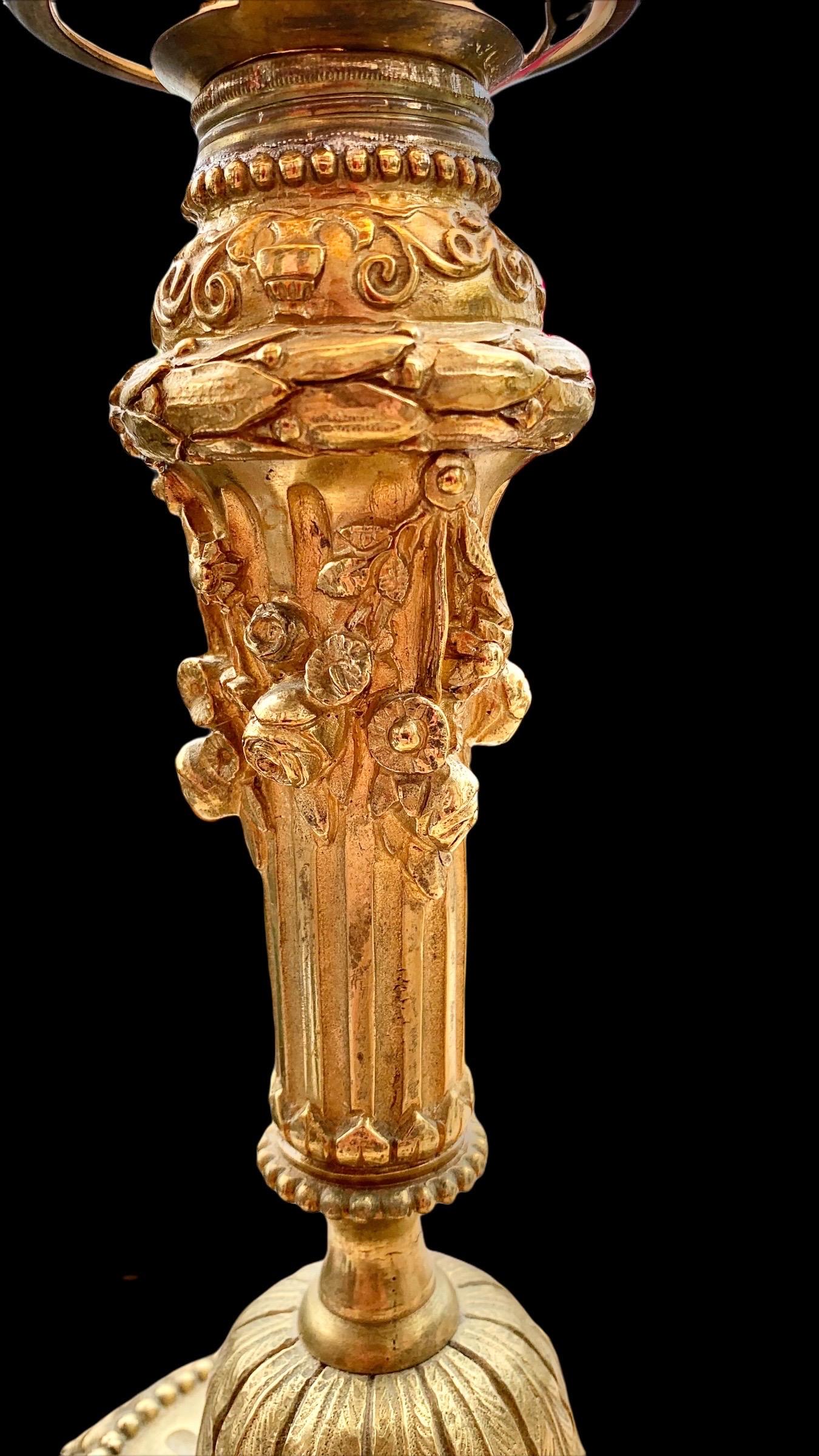 An exquisite example of the French Belle Epoch period gilded bronze candle stick lamp, beautifully cast with floral garlands and flowers, the base encircled with petals and flowers. The flame shade frosted and lovely. A piece of French history of