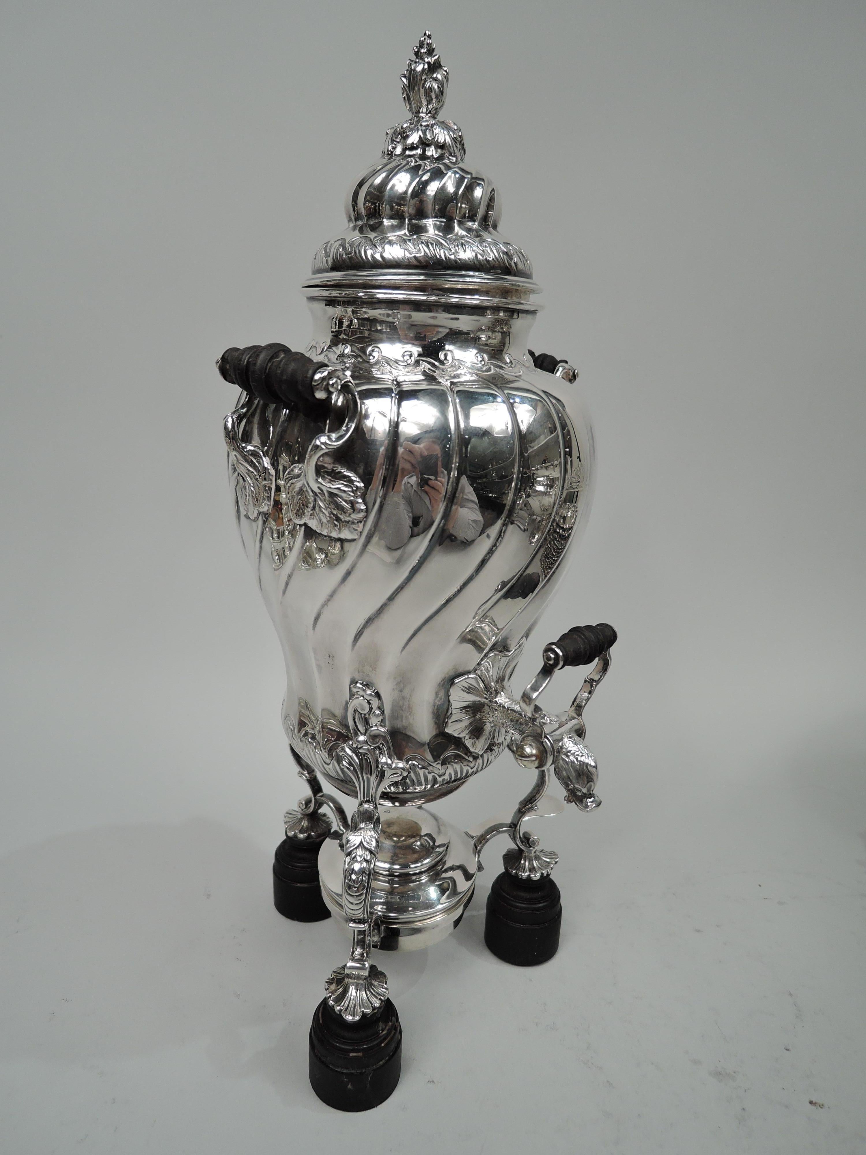 French Belle Epoque classical 950 silver tea urn, ca 1900. Ovoid with turned stained-wood handles with silver scroll and leaf mounts. Scaly fish spout with tail mount and gaping mouth spout and turned stained wood and silver scroll tap. Double-domed