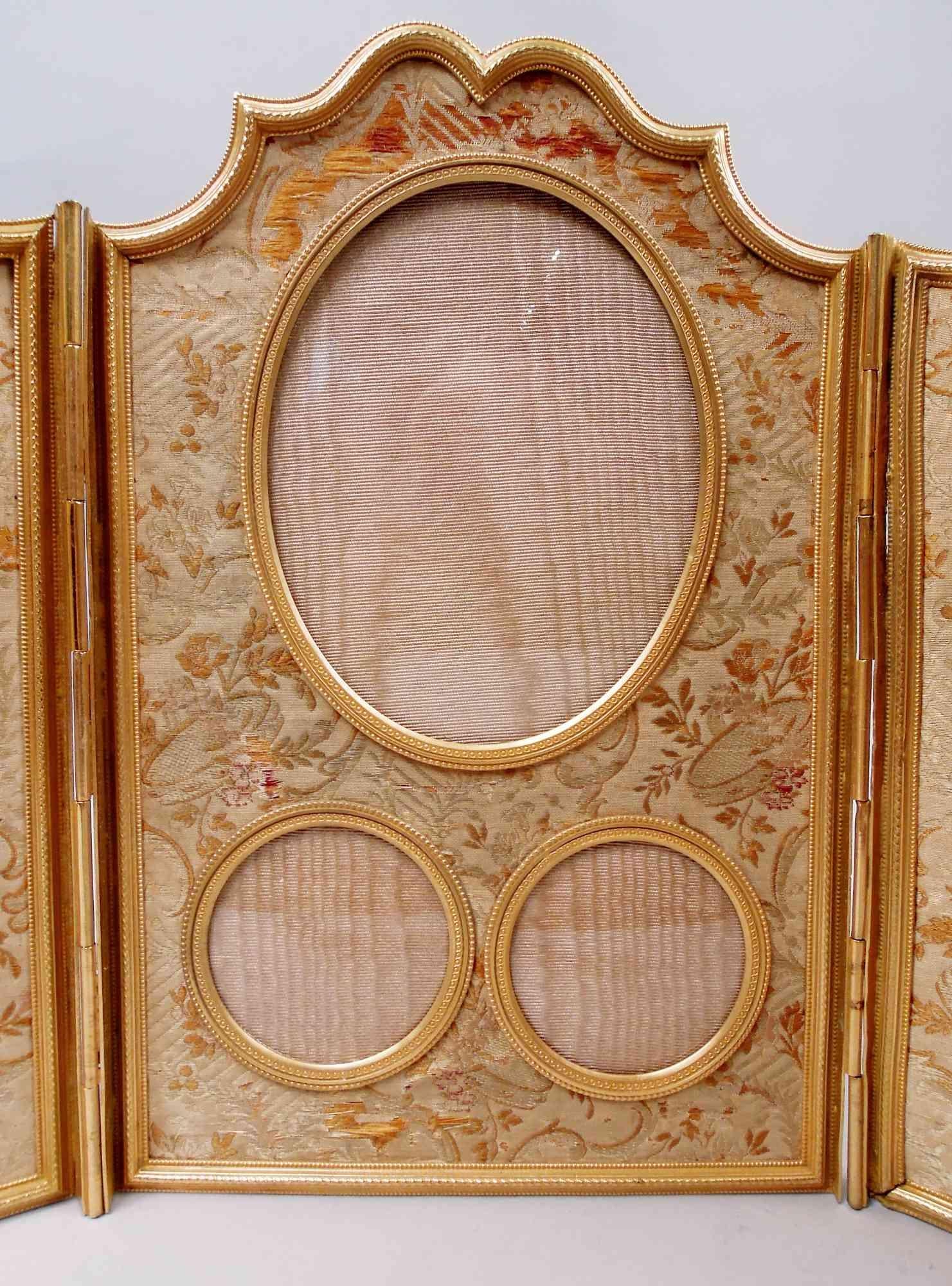 Marco tríptico de bronce dorado de la French Belle Epoque, hacia 1900. Tres soportes articulados y perfilados con bordes de cuentas y guilloches. Suelo textil floral. Con cristal y forro de seda.
Siete ventanas en total: 2 redondas (D 3 3/8), 2