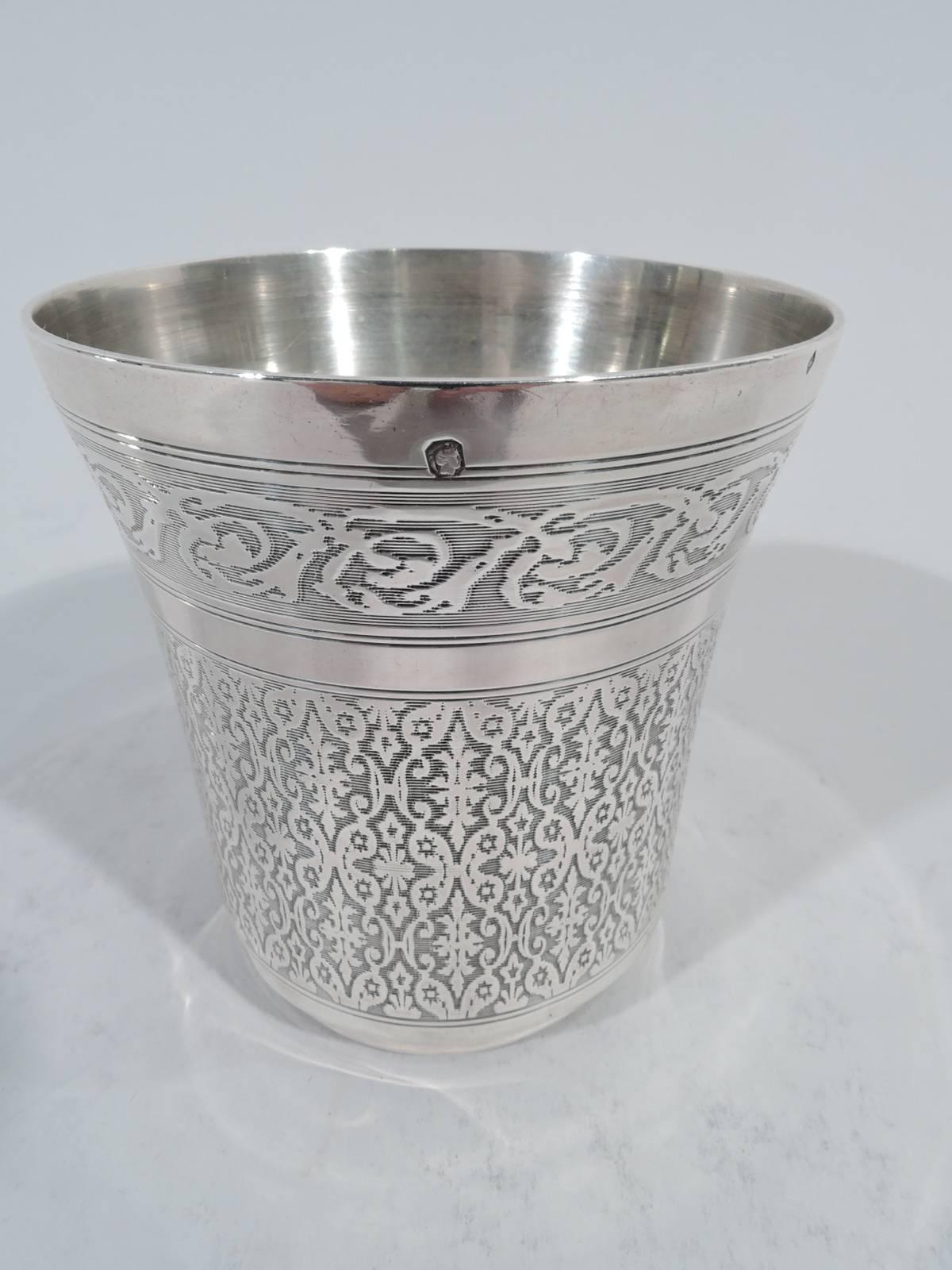 Belle Époque French 950 silver beaker. Flared rim and short inset foot. Dense strapwork and rinceaux on reeded ground. A symmetrical frame with flowers and interlaced script monogram. Minerva head and maker’s initials AL. Weight: 3 troy ounces.