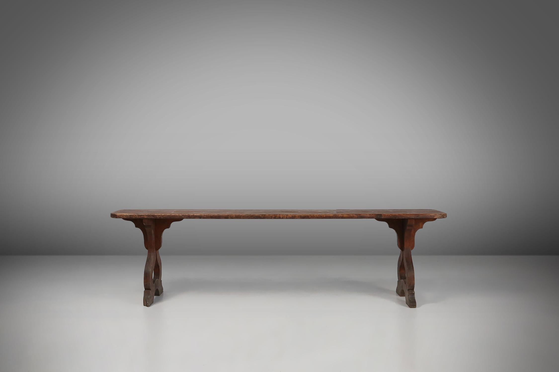 An interesting wooden bench, with decorative elegant carved base and rounded wooden top with brilliant grain. This bench is meticulously handcrafted using the finest quality wood, ensuring durability and longevity. Its compact size makes it perfect