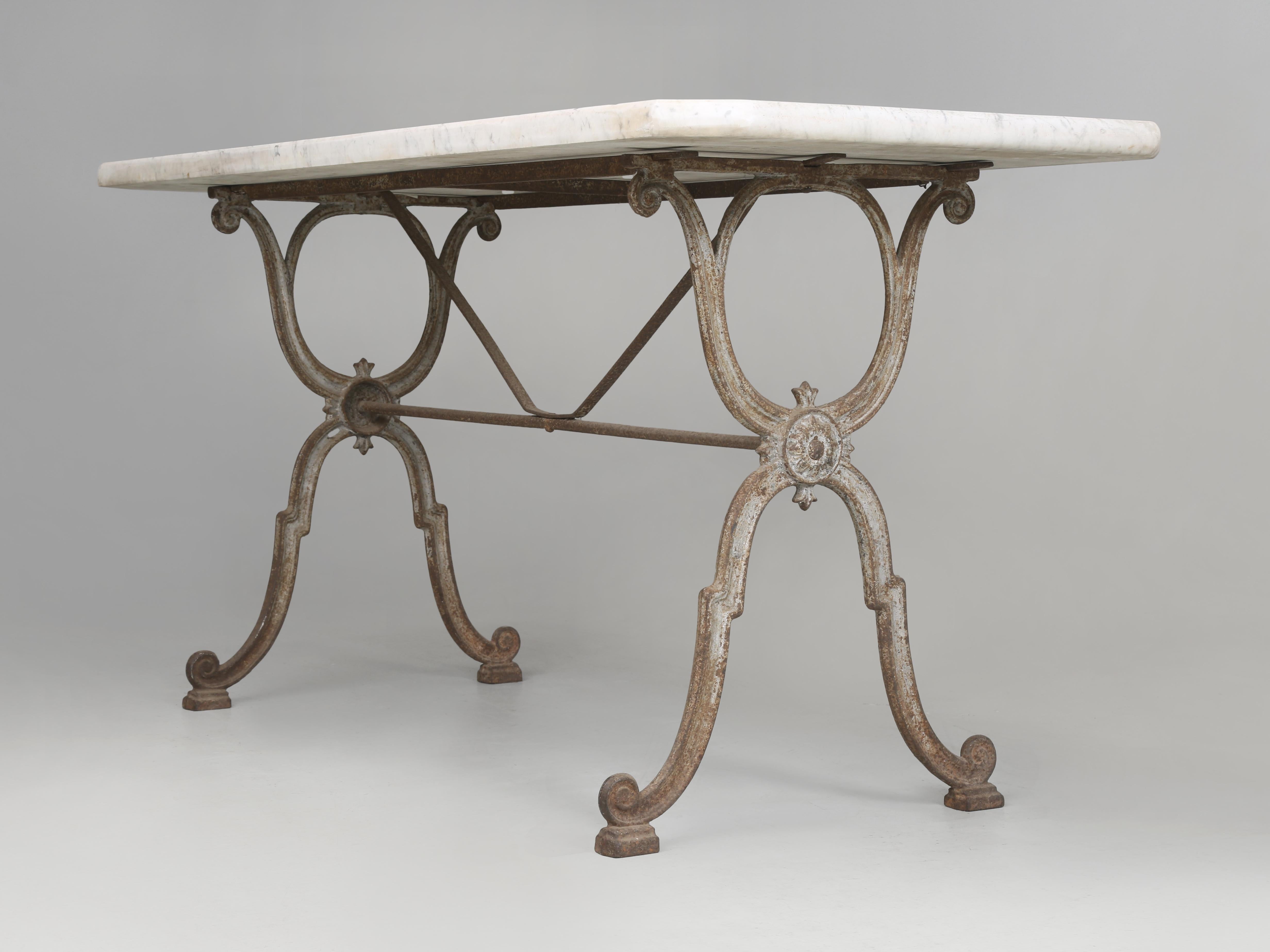 Ancienne table de bistrot française du début des années 1900. Notre base en fonte française présente encore quelques vestiges de la vieille peinture grise, combinée à un incroyable plateau en marbre épais aux coins inclinés. Peut être utilisée comme