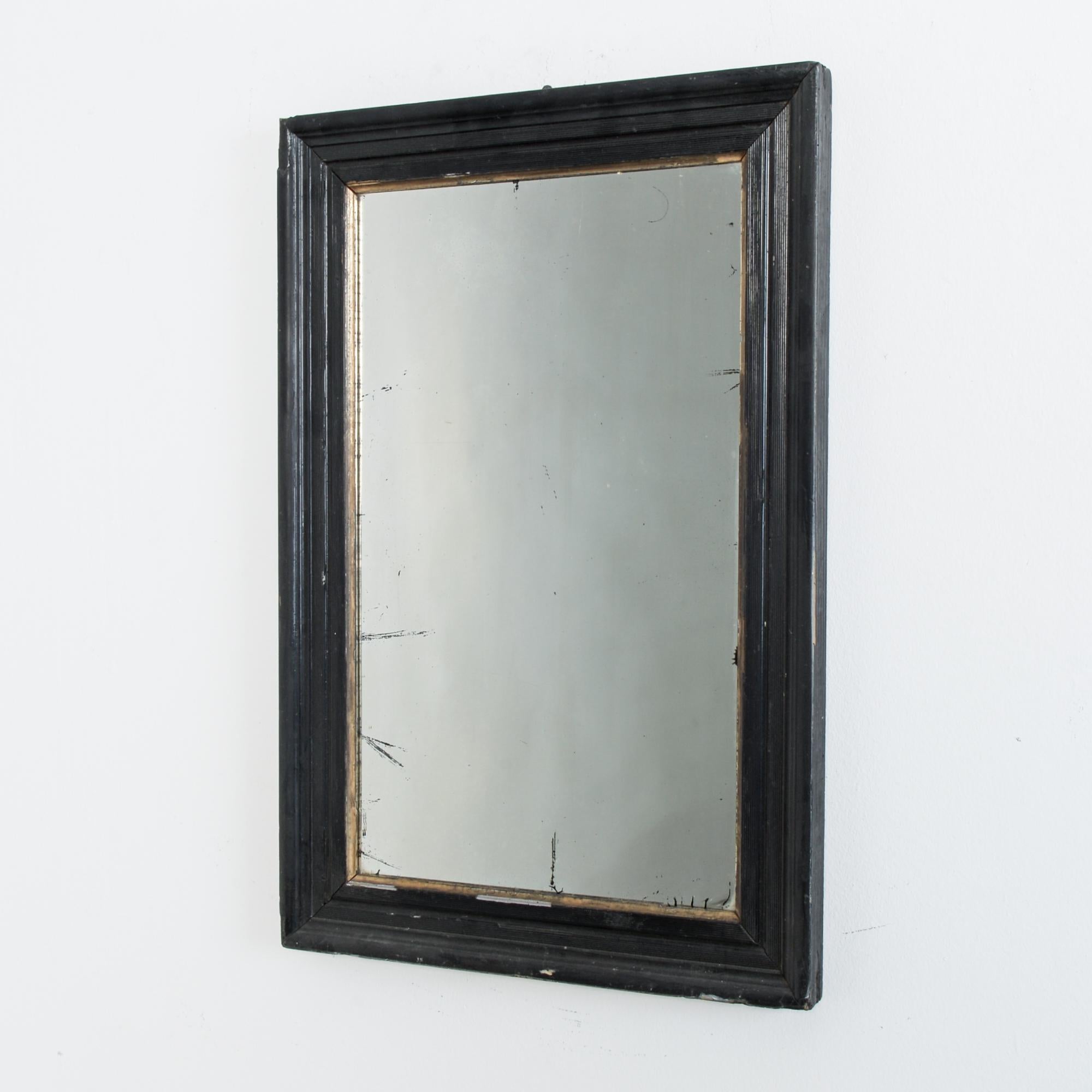 From France, circa 1900. This simple black lacquered mirror in a simplified Napoleon III style. A great rustic patina, features gilded inset moulding and original mercury glass mirror with characteristic patina.
   