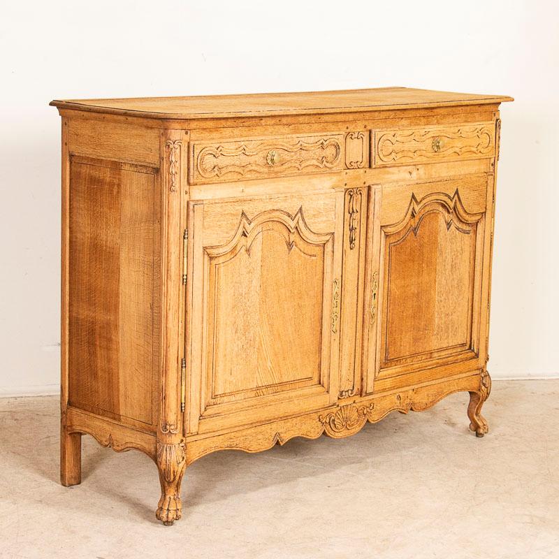 It is the lovely carved details and heavily paneled doors that draws one to this French oak sideboard. The bleached finish gives it a fresh and welcoming look for today's modern home and shows off the wonderful grain. The attractive scalloped skirt