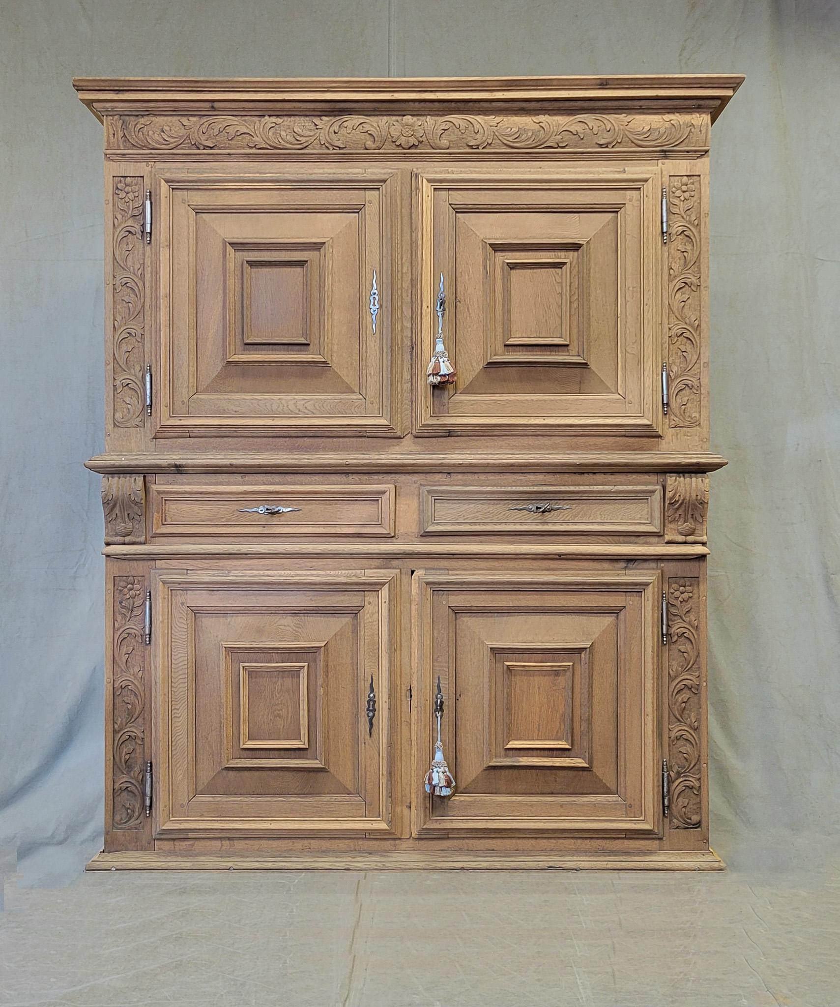 A beautiful antique early 1800s French carved oak and pine two piece cabinet that has been bleached for a lighter, rustic European look. Large compartments with shelves for storage above and below with two drawers. All doors and drawers are