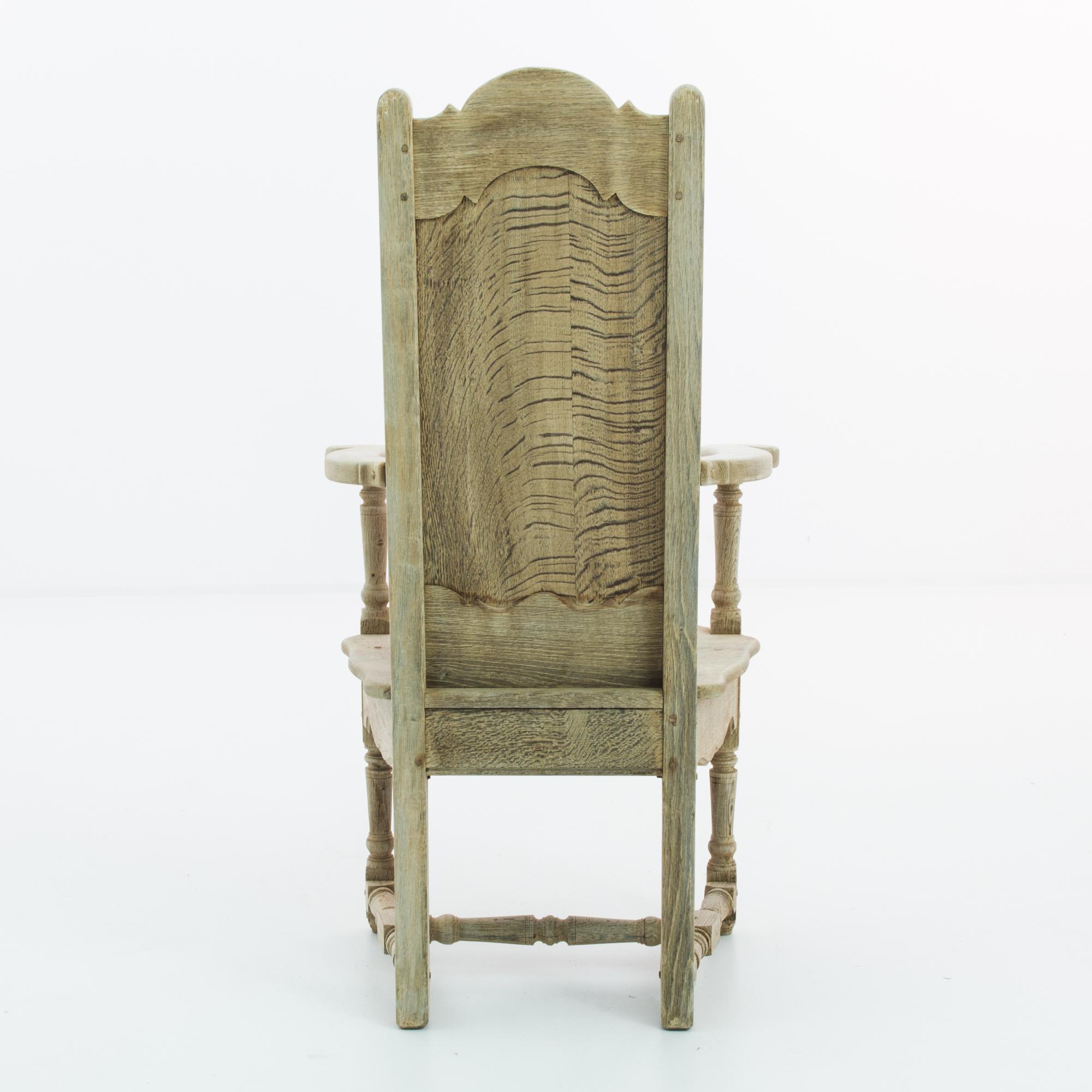 Made in France, this bleached oak armchair offers old-world charm with its elaborate carvings. The apron and back are carved with a lattice, while refined paneling features on the center of the backrest. Contoured armrests and turned legs give this