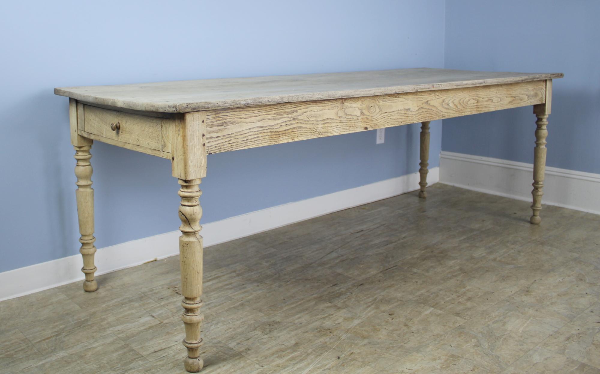 A slim graceful French oak farm table, bleached for a modern casual look. The eye-catching turned legs add a whimsical note, as do the two end drawers. With 79 inches between the legs on the long side, this table can comfortably accommodate 8. 24