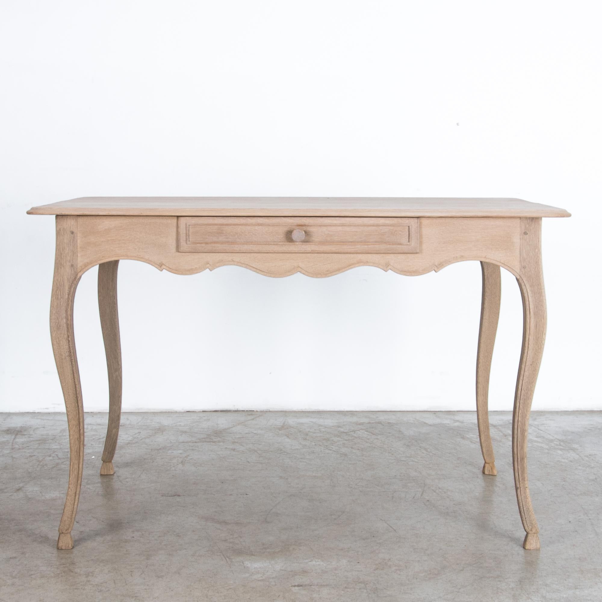 A simple oak table with center drawer, from France, circa 1900. Rustic yet refined, this oak table is crafted after the traditions of local craftsmen. Away from the capital, carpenters interpreted the latest fashion in pared down styles, recalling