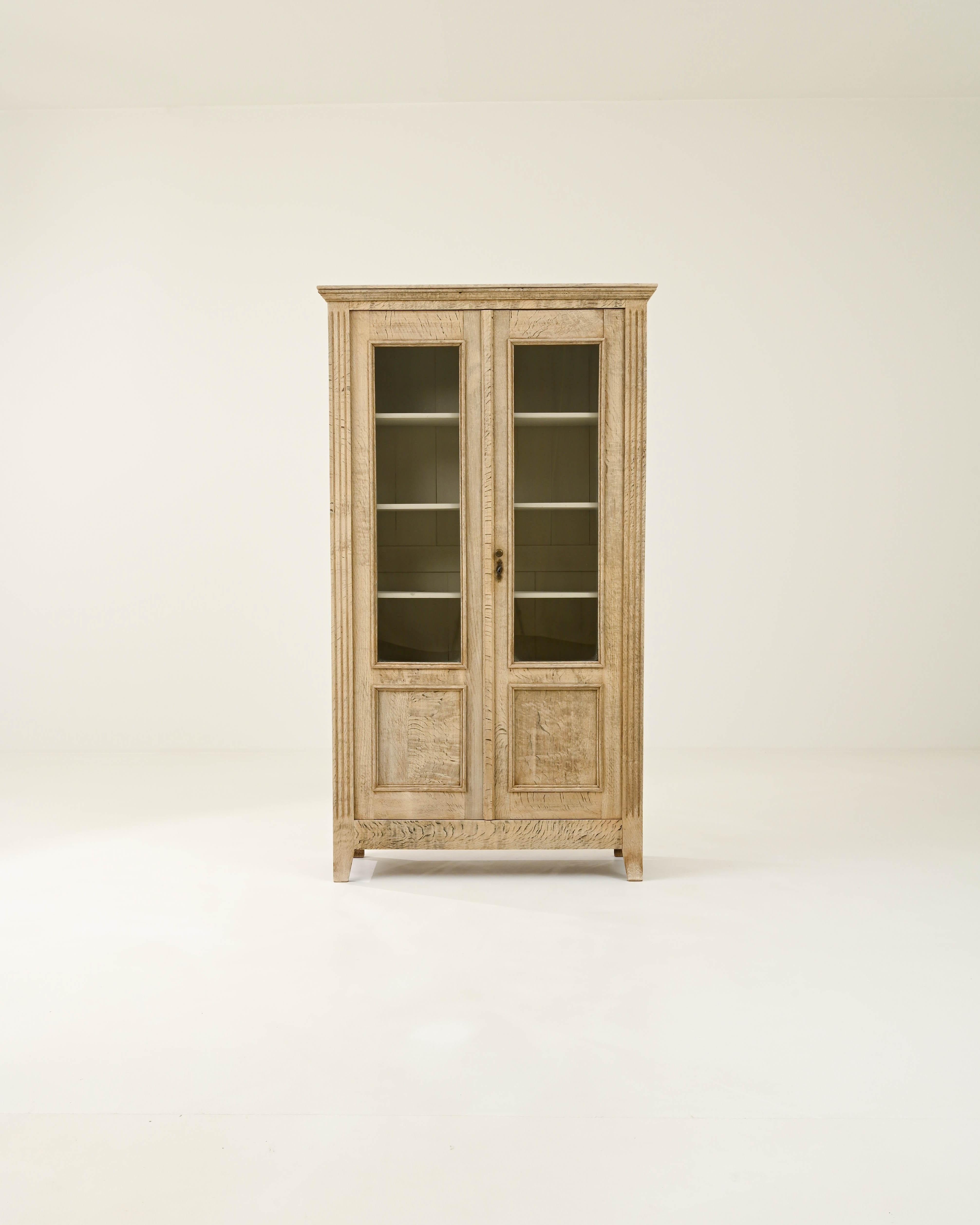 Imposing as the oak tree that allowed the birth of this vitrine from the nineteenth century, this piece has stood strong through the years. Carved with neoclassical decorations resembling the architecture of the era, this cabinet serves as a