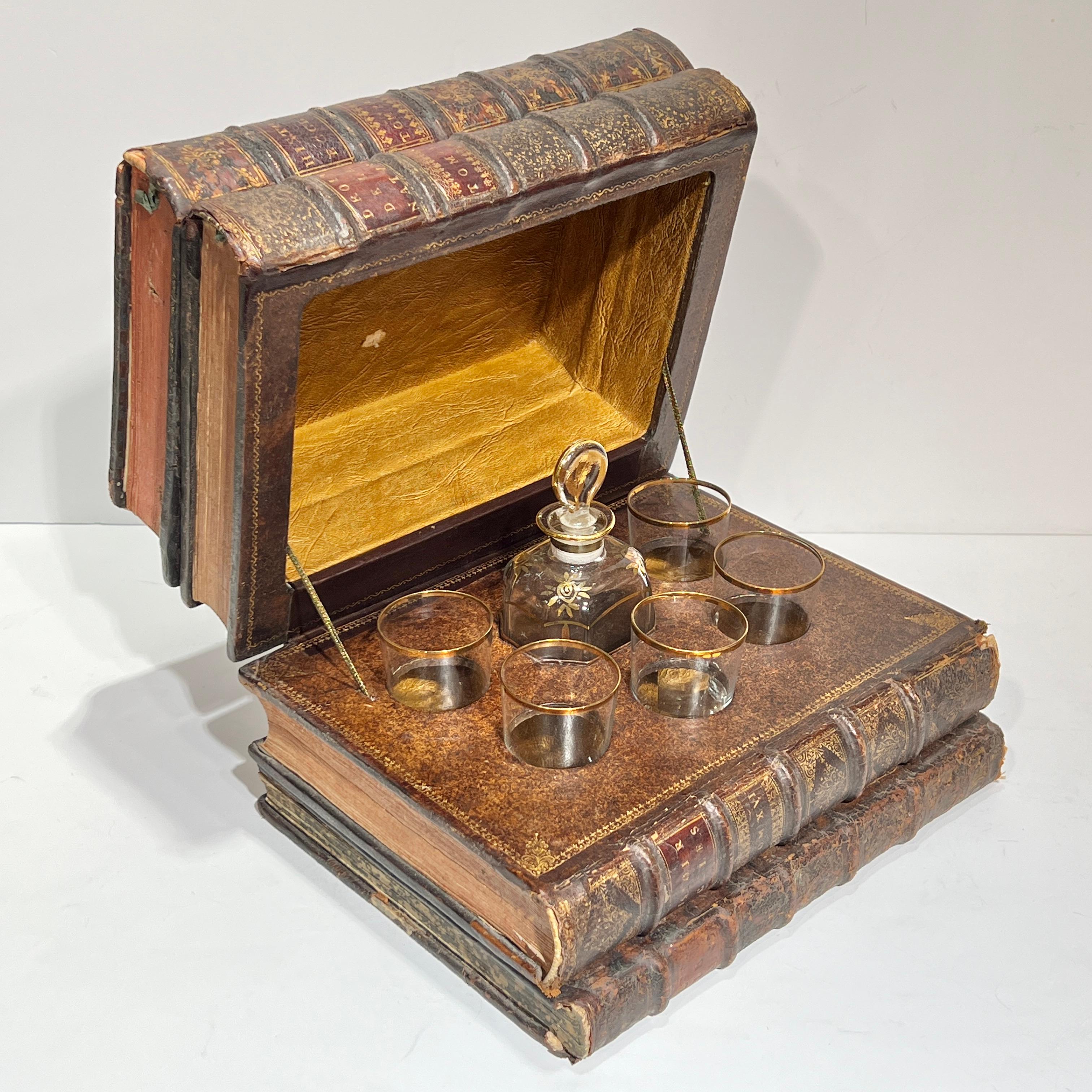 Tantale français ancien (fin 19e - début 20e siècle) sous forme de quatre livres reliés en cuir empilés avec des titres en latin, avec une carafe en verre doré et cinq verres, idéal pour les liqueurs de tout type, en particulier le whisky, le seigle