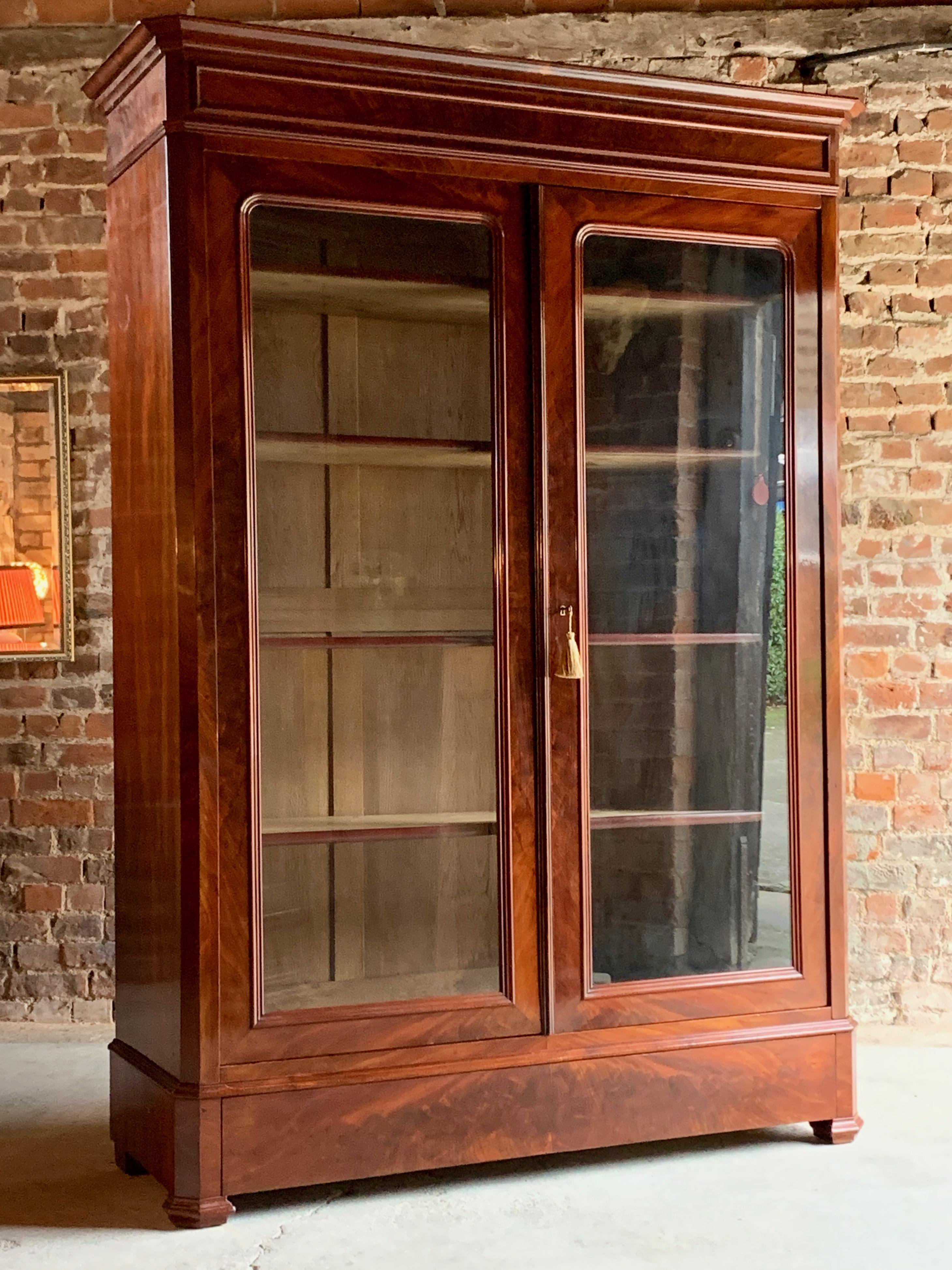 Antique 19th century French flamed mahogany bookcase vitrine, circa 1875

A fabulous 19th century French flamed mahogany two-door bookcase vitrine, circa 1875, the large overhanging cornice above two glazed doors with four adjustable shelves