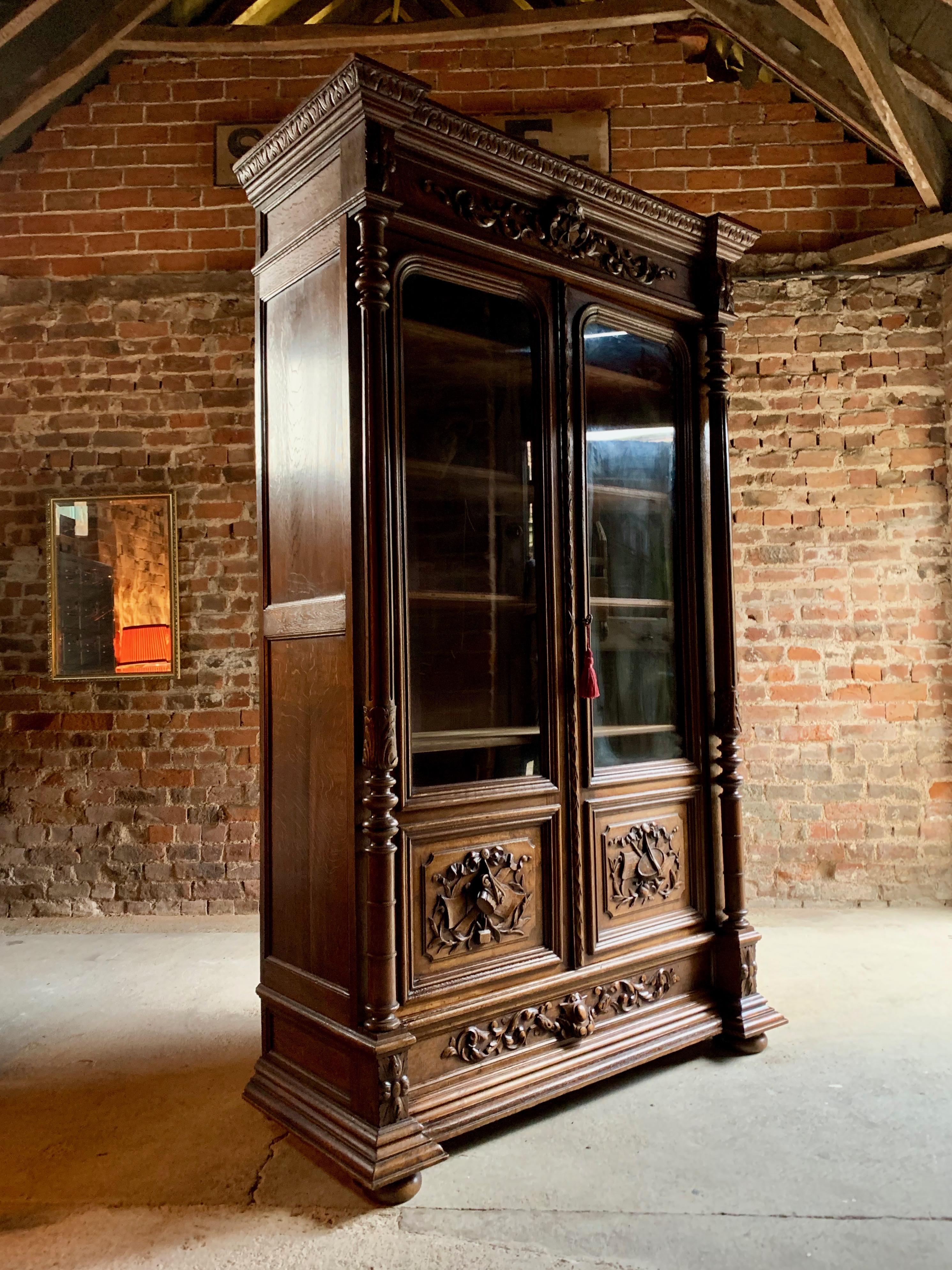 Antique 19th century French solid oak bookcase vitrine, circa 1890.

A large 19th century French profusely carved solid oak two-door bookcase vitrine circa 1890, the ornate overhanging molded carved cornice above two heavily carved paneled glazed