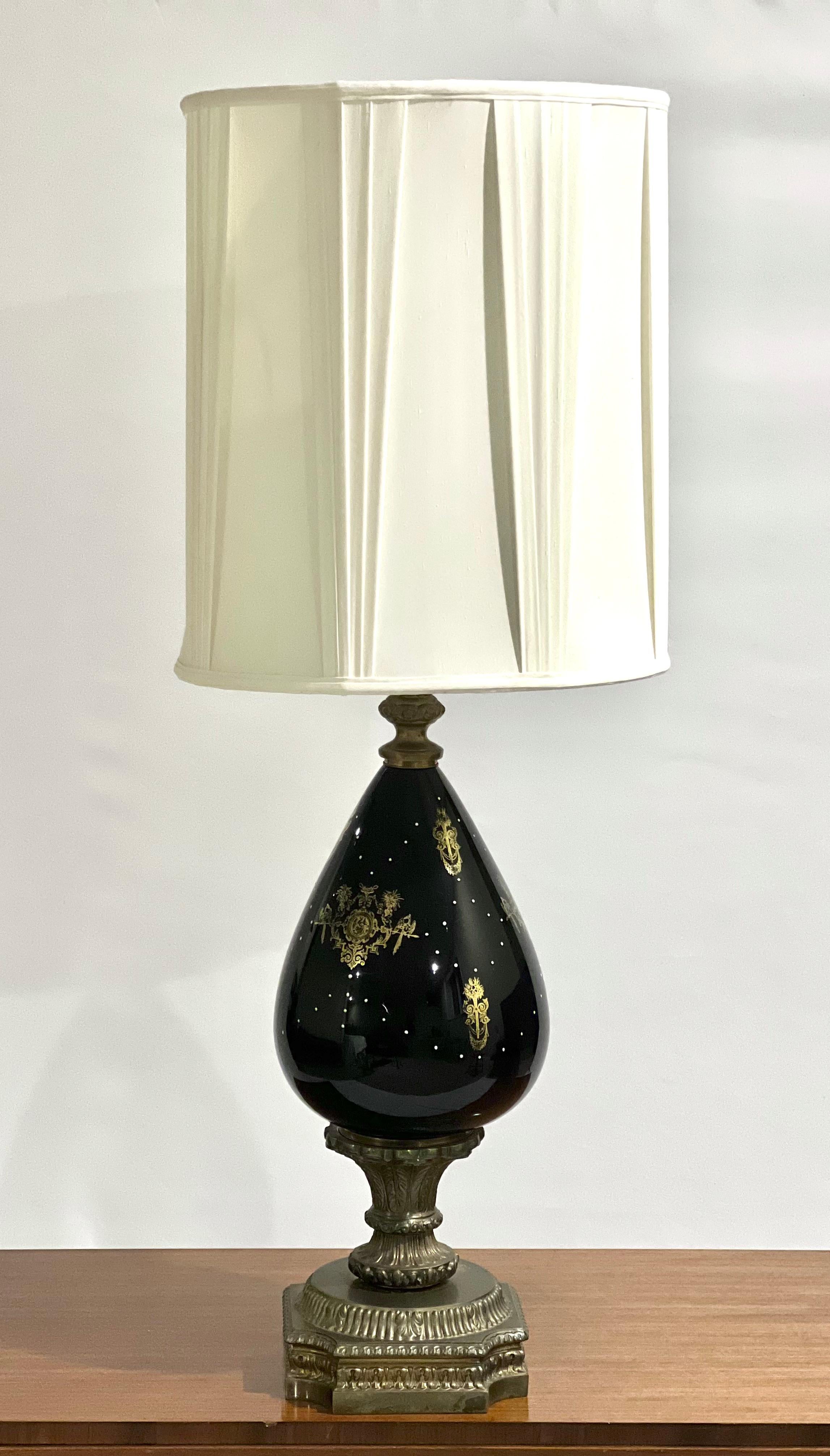 Antique French porcelain and brass table lamp with shade, France circa 1890.

Impressive mirror noir vase lamp with a gilded brass ormolu base and acanthus leaf detail. The body features hand painted gold double griffin heraldic emblems and white