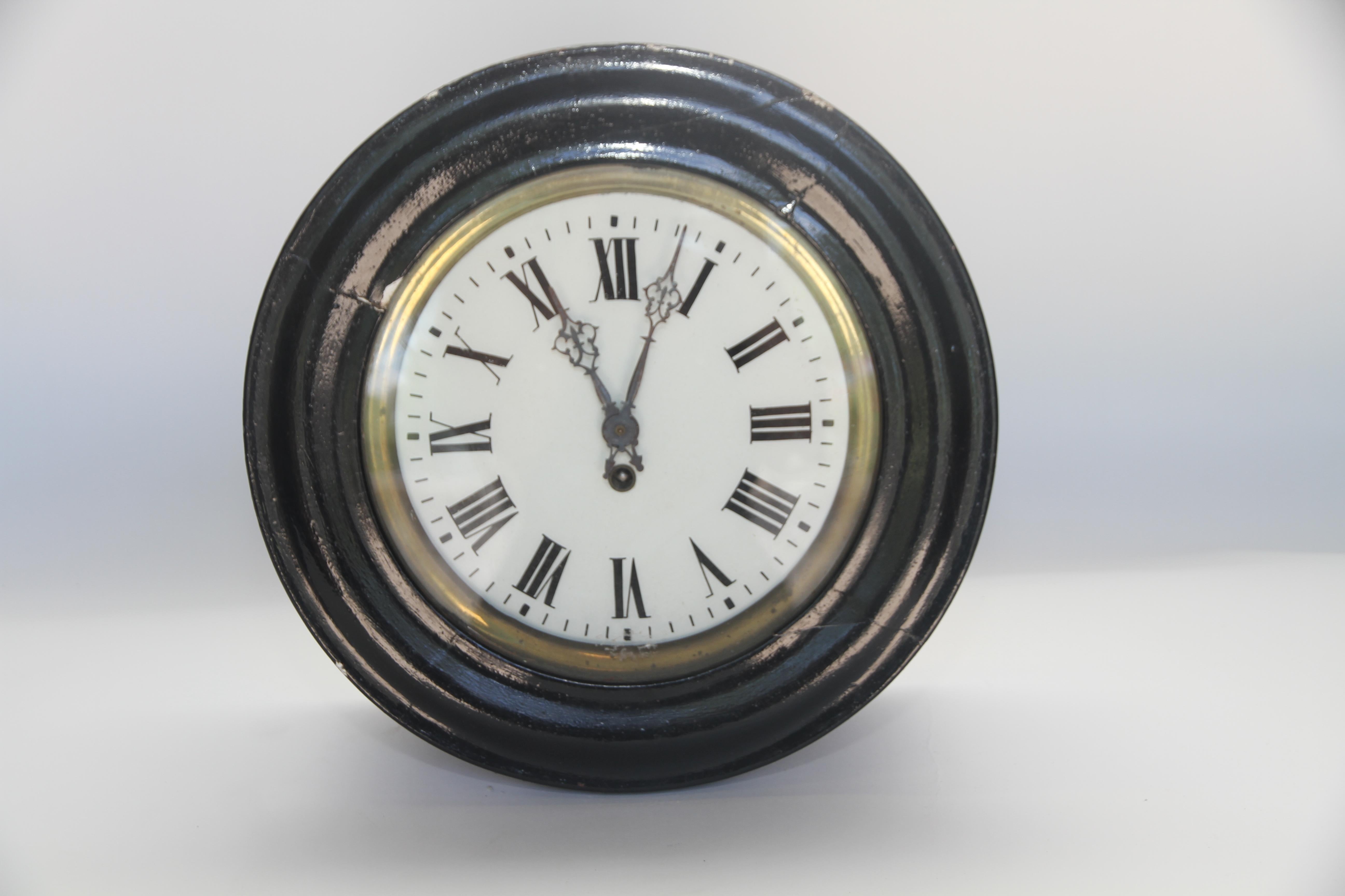 A lovely antique French wall clock made of brass and wood. The wood has been painted in a black gloss finish, the glass in the door is intact with a brass insert which surrounds the glass face of the clock when closed. The face is decorated with