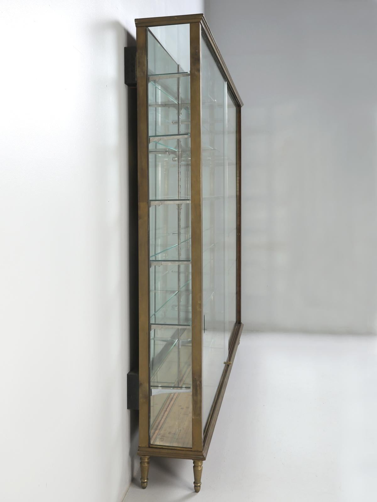 Antique French brass cabinet with glass sliding doors. We are guessing that this may have been specially built for a high-end department store, at around the turn of the century. The glass doors do have there share of chips and missing areas, but