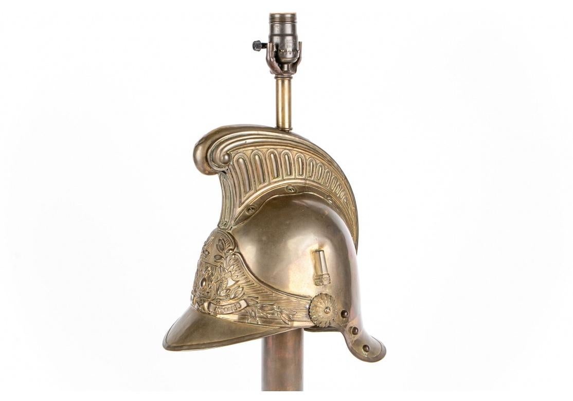 Well made in a ceremonial fashion in the manner of an ancient Classical helmet. Mounted on a carved and black painted wood base. The helmet inscribed, “Srs. POMPIERS De AVERNES” above the front rim. 
Measures: Height 23