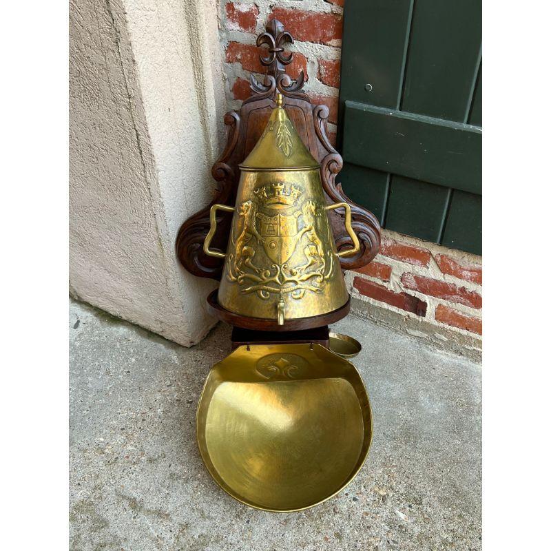 Antique French Brass Lavabo Fountain Carved Oak Wall Mount Crest Catholic Mass.

Direct from France, a very special French lavabo or wall fountain!
A carved fleur de lis crown atop the large, serpentine carved oak panel, which provides the perfect