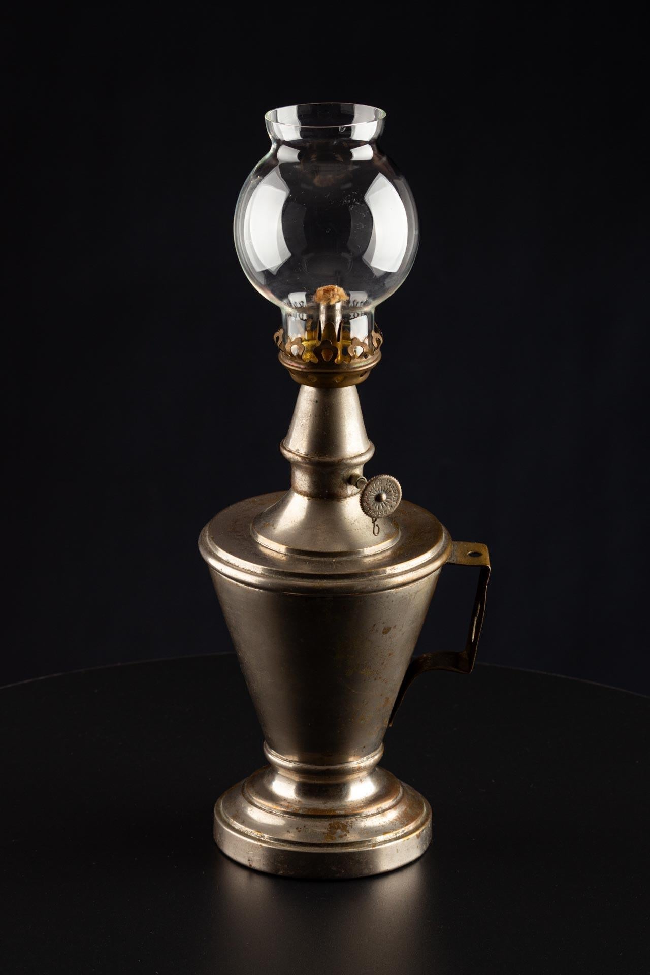 Realizzata alla fine del XIX secolo in Francia, questa lampada a olio in ottone nichelato rappresenta uno sviluppo significativo nella storia dell'illuminazione. Conosciuta come lampada Pigeon, era un tipo di lampada a olio portatile molto diffusa
