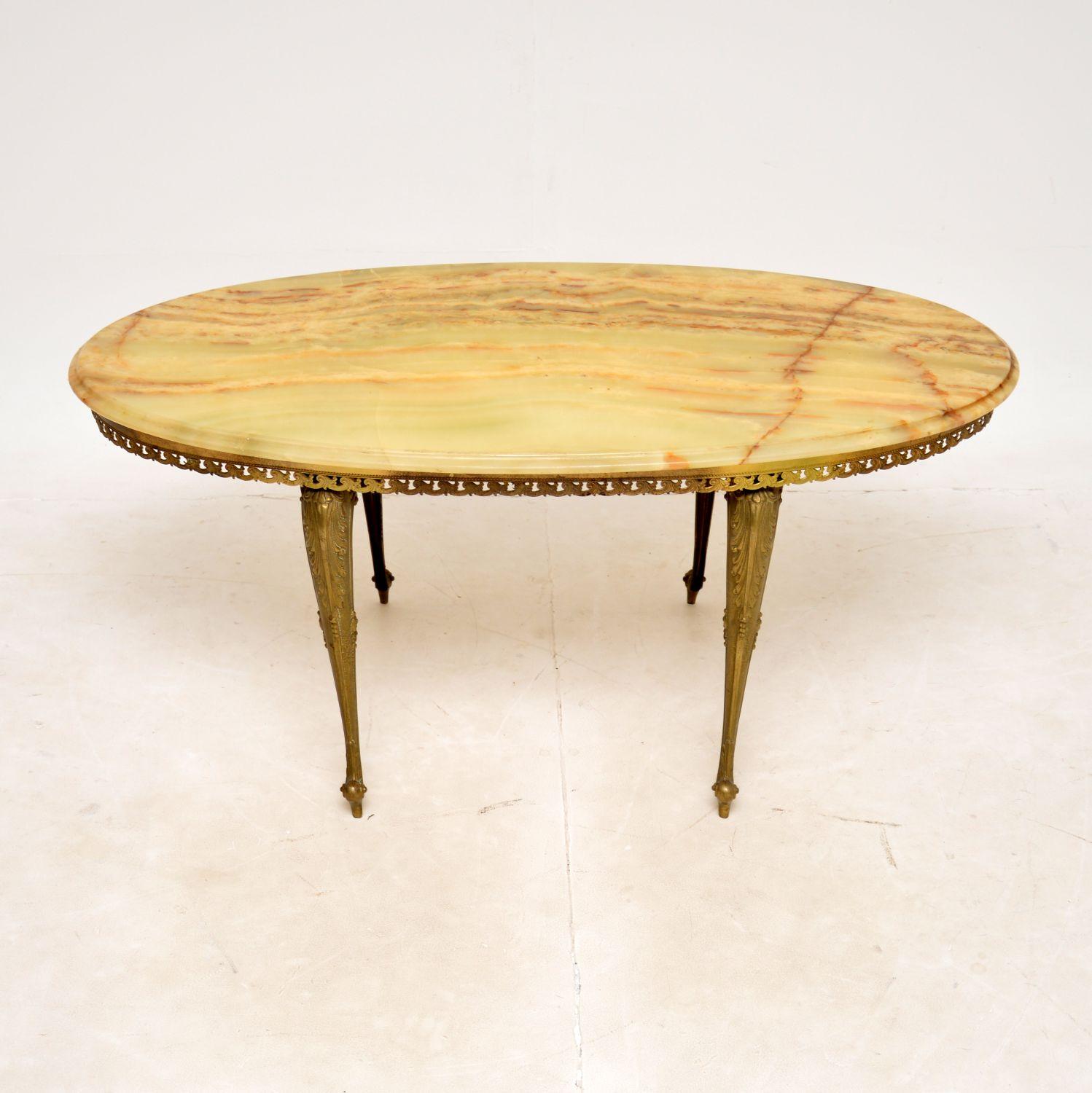 A beautiful and elegant antique French coffee table with a brass frame and oval onyx top, dating from around the 1930s.

This has a stylish design and is a very useful Size. The brass frame has gorgeous details, the onyx top has stunning colours