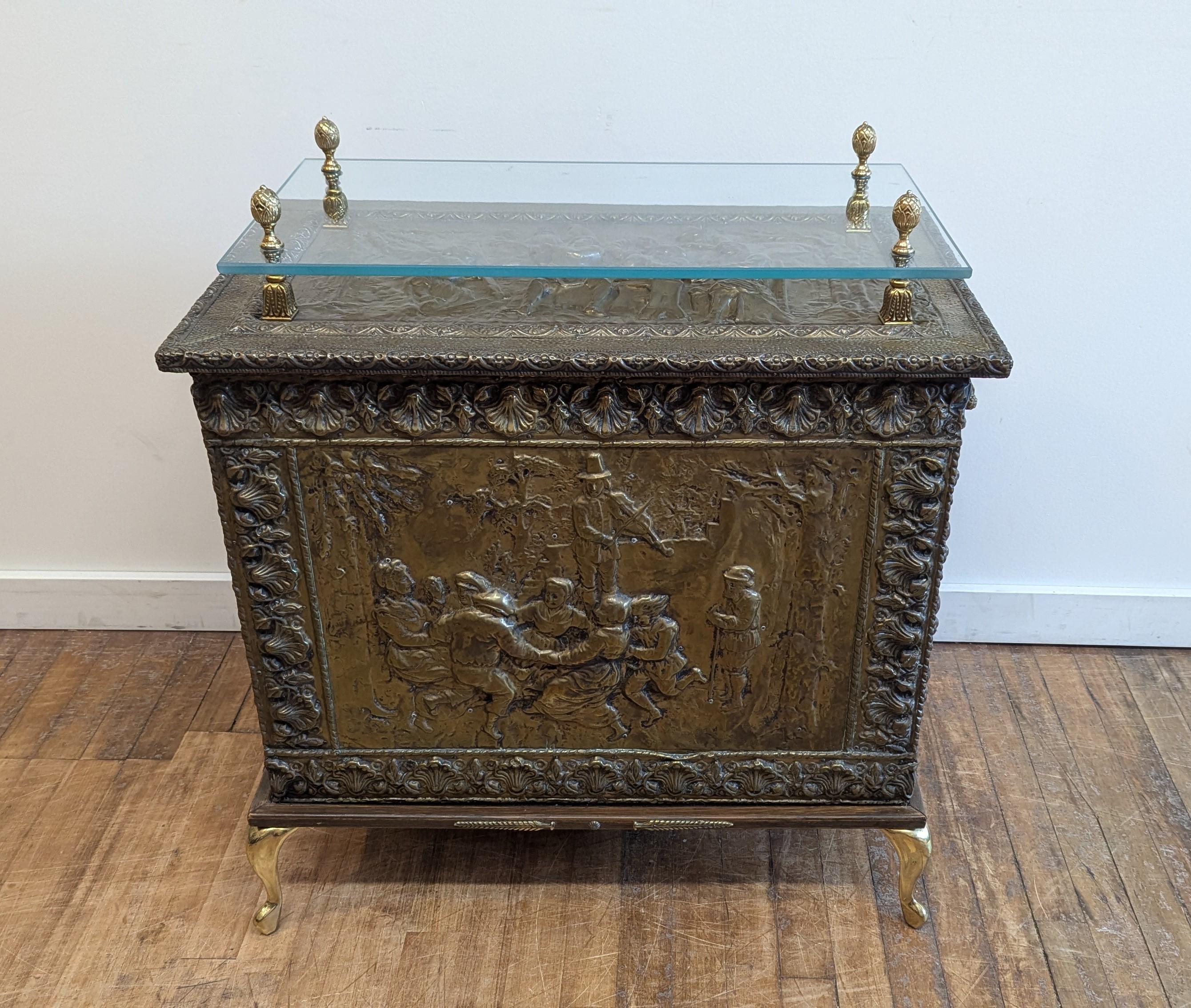 An adapted early 20th century French Brass repousse Firewood Box.  This beautifully hand crafted firewood box has been adapted into a table or console.  Brass cabriole feet, brass handles and a glass top was added to this piece in the 1960's