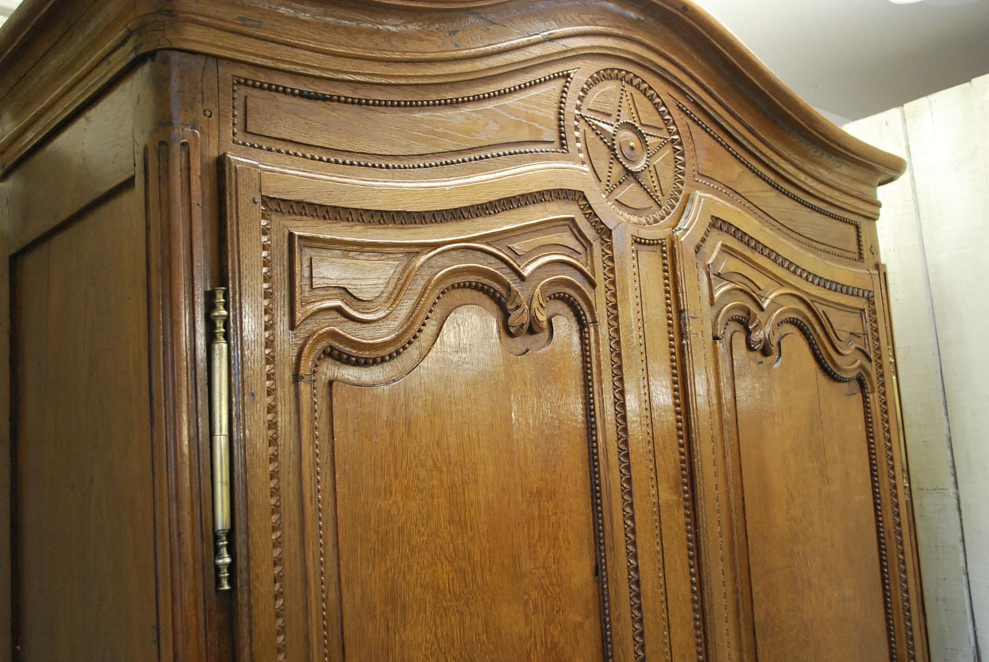 A lovely example of a contemporary looking French armoire that looks both decorative and traditional. Made in beautifully patinated light oak with fine ball decoration on shaped panelled doors. Beautifully carved star decoration to the cornice and