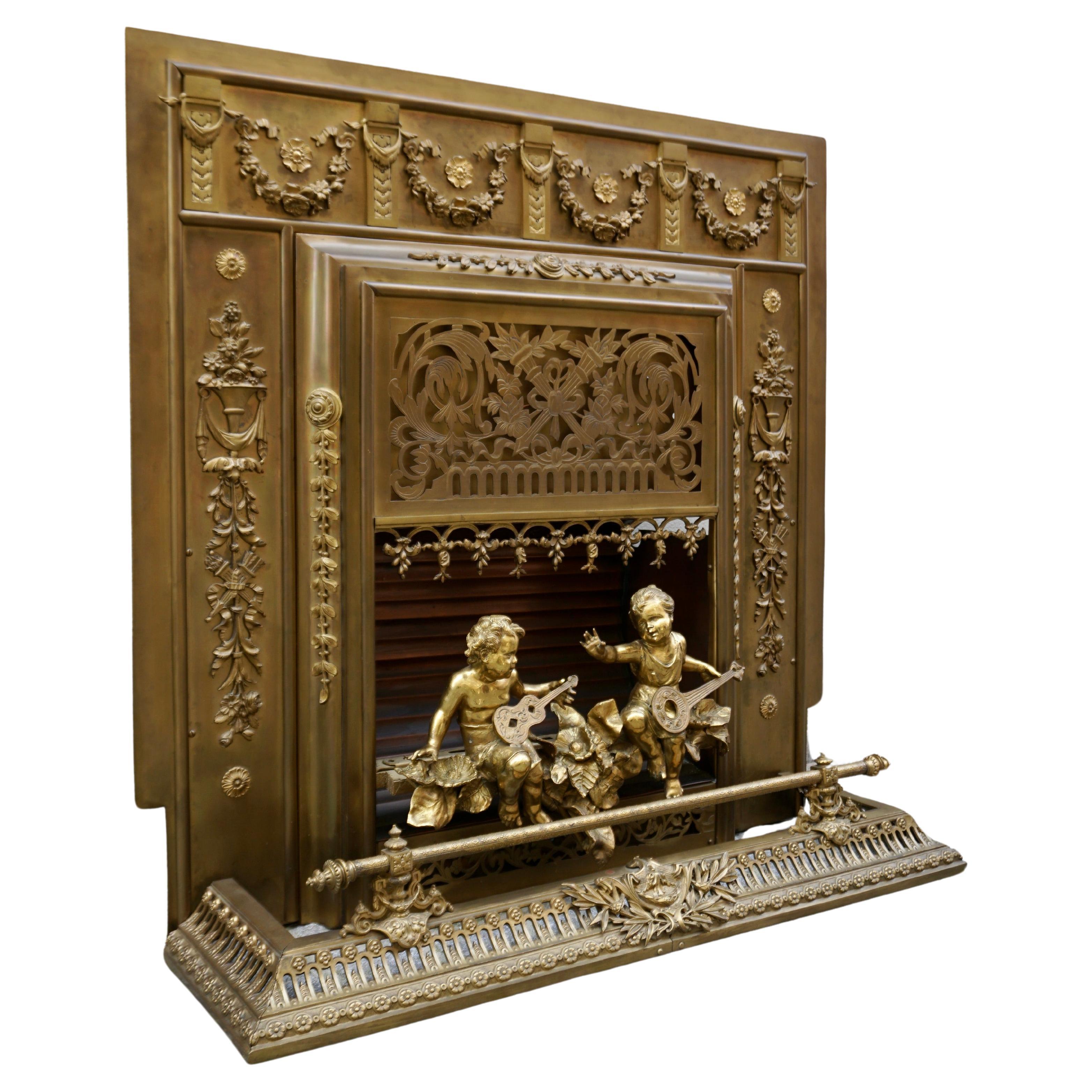 Un inserto per caminetto in ottone antico molto decorato con dettagli intricati. Il design presenta motivi classici, tra cui ghirlande floreali e intricate volute, caratteristiche dell'artigianato europeo del XIX secolo. Il punto focale dell'inserto