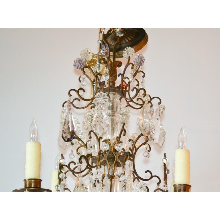 Fabulous antique French gilt bronze and crystal chandelier with an abundance of scrolled features lavished with polished almond-shaped prisms, pendeloque cut crystals, amethyst-tinted flower heads, icicle drops, small crystal spheres, and pale pink