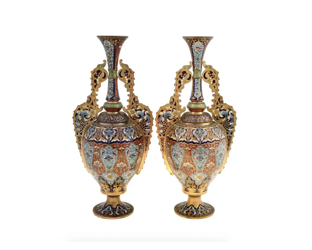 A pair of antique mid-19th century French gilt bronze vases. The elongated form with figurative handles is often referred to as Alhambra, meaning of Oriental or Moorish taste. The pieces are richly decorated with blue and green floral champleve