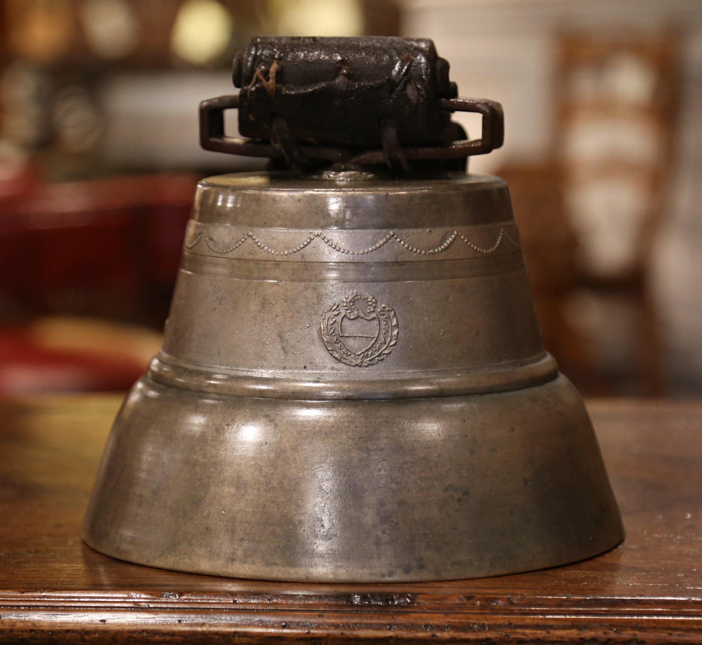 Bring the French countryside into your home with this large patinated bronze bell from the Alps region of France, dated 1900, the antique bell features several motifs in relief including garland decor around the top, flower and crest motifs. The