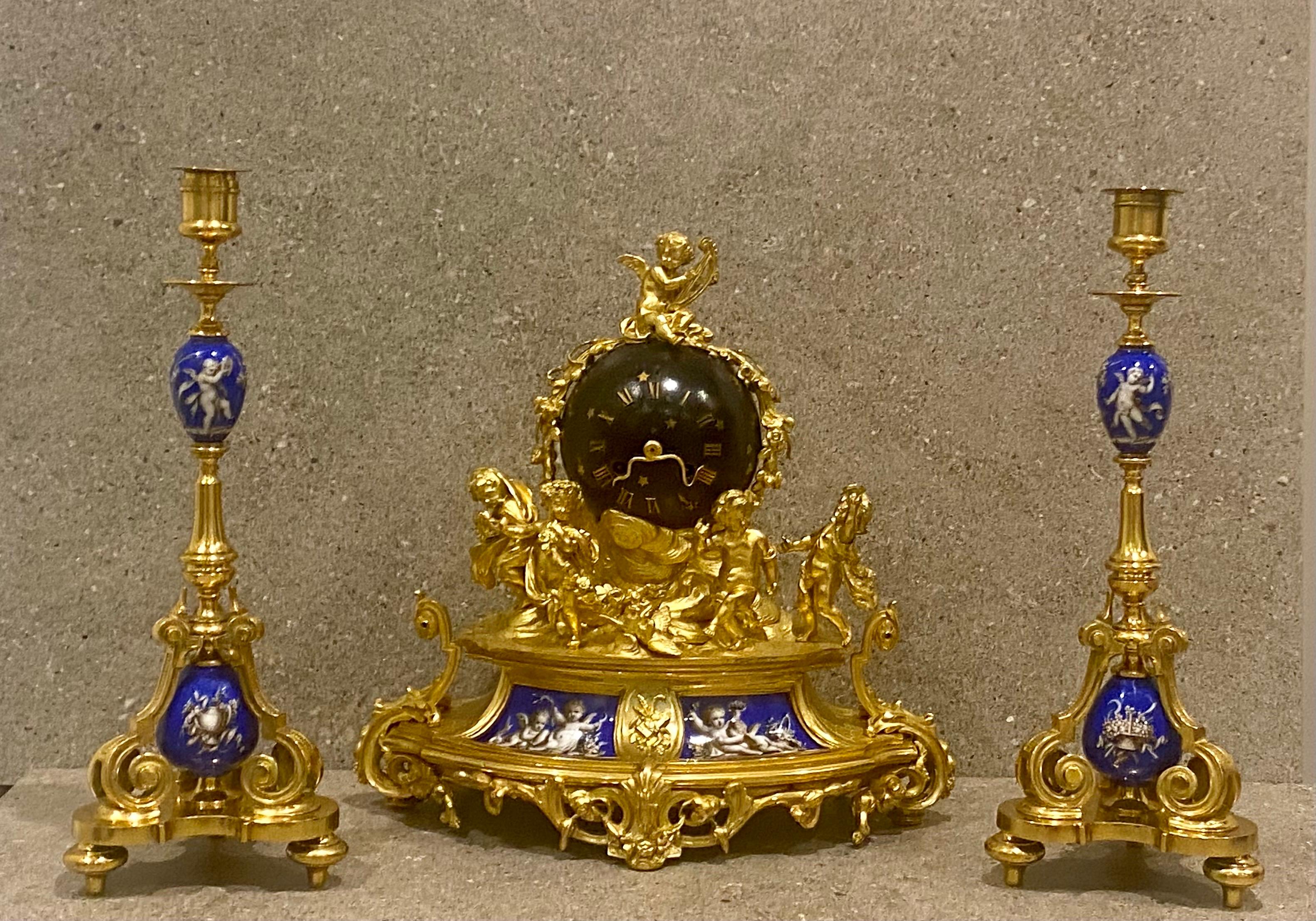 A beautifully detailed three piece clock garniture; in Porcelain with a bronze dore finish, after the model by Clodion. 19th Century
The clock featuring five young bacchante figures, An original blue enamel metal globe containing movement, dial