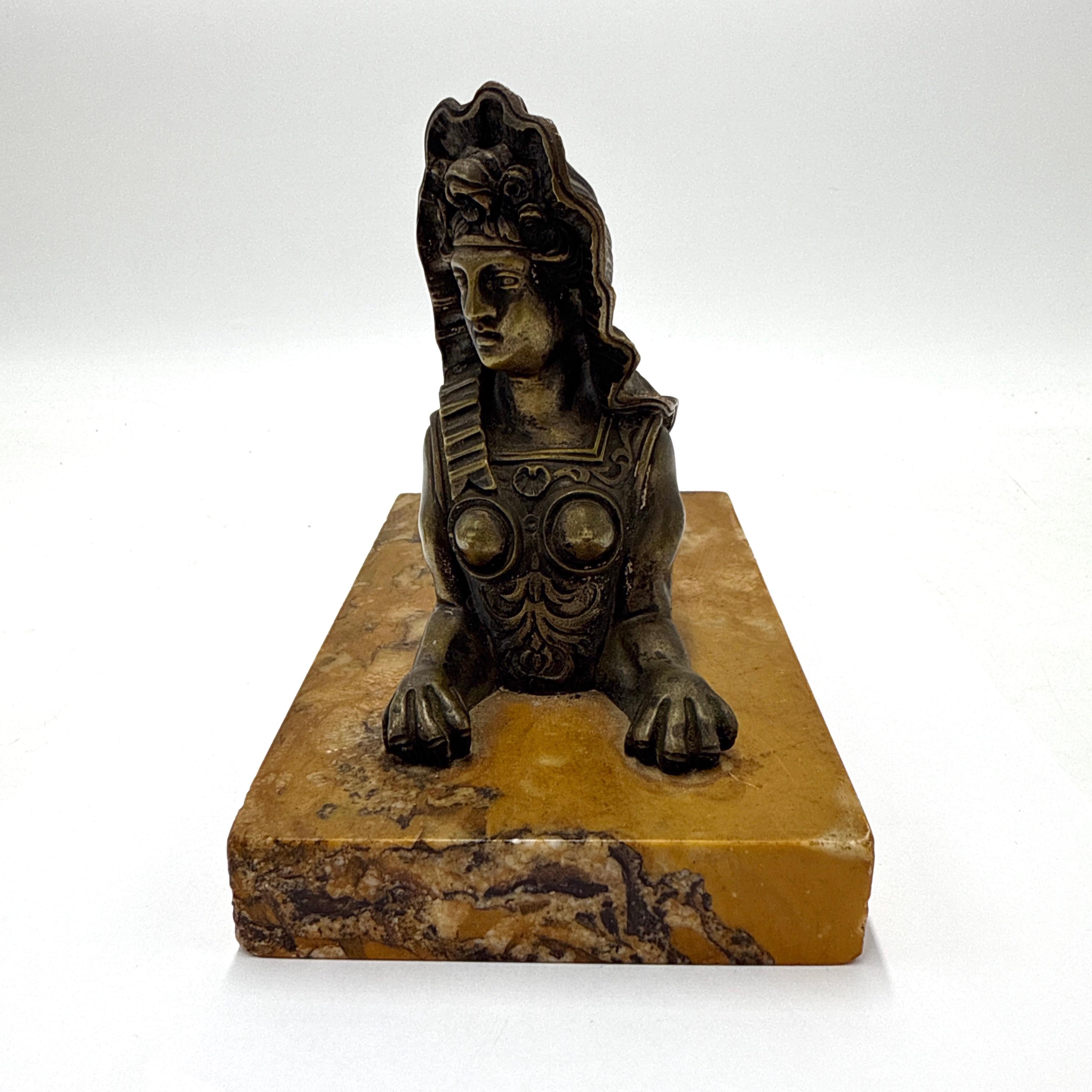 A finely cast French bronze sculpture in the Egyptian Revival style, likely dating to the late 19th or early 20th century. The figure represents a female sphinx, detailed with classical armor and a stylized nemes headdress. The figure is mounted on