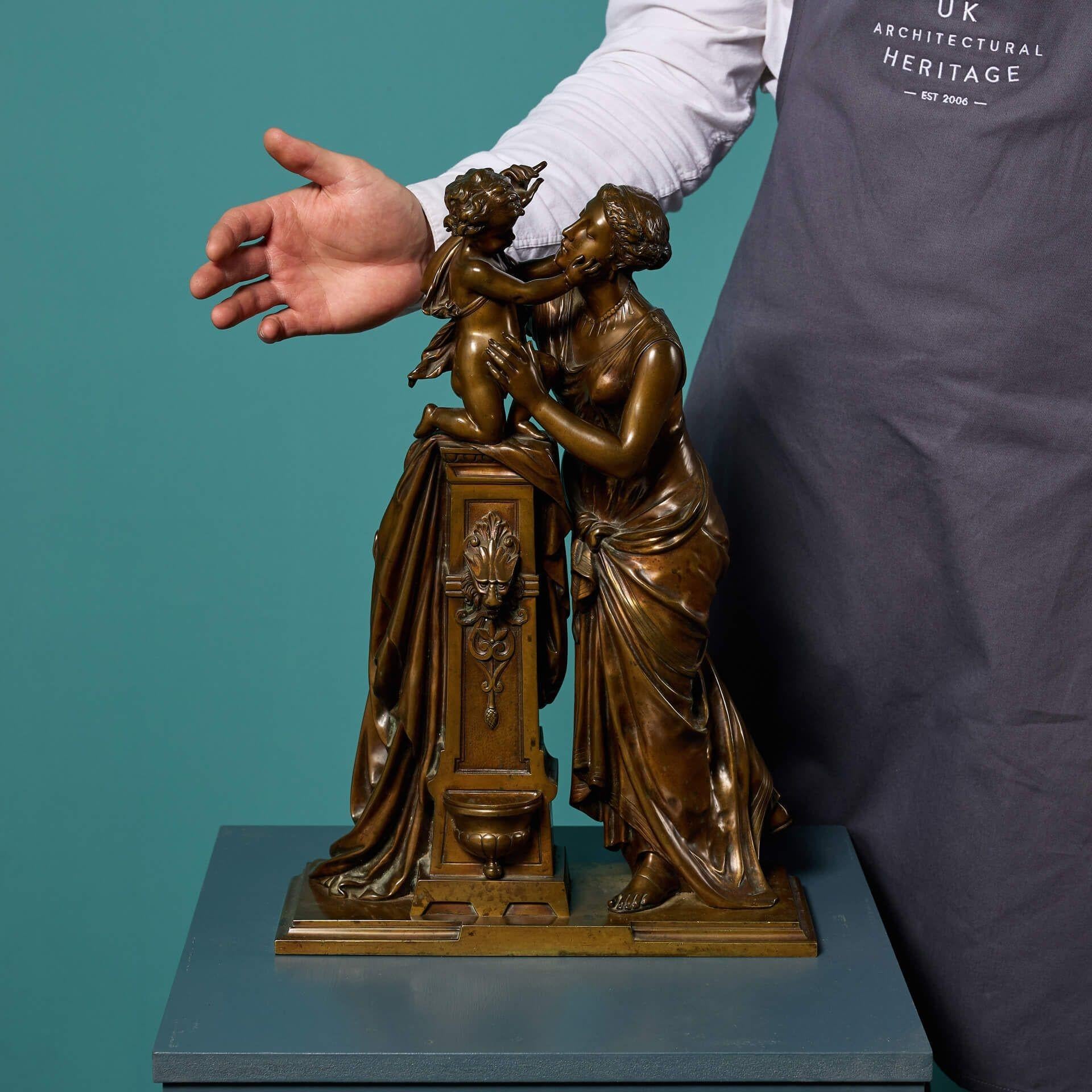 Sculpture ancienne en bronze français représentant une mère et son enfant, à la manière de Jean-Jacques Pradier.

Datant de la fin du XIXe siècle, cette figure debout est représentée jouant affectueusement avec l'enfant sur une fontaine.

Posée sur