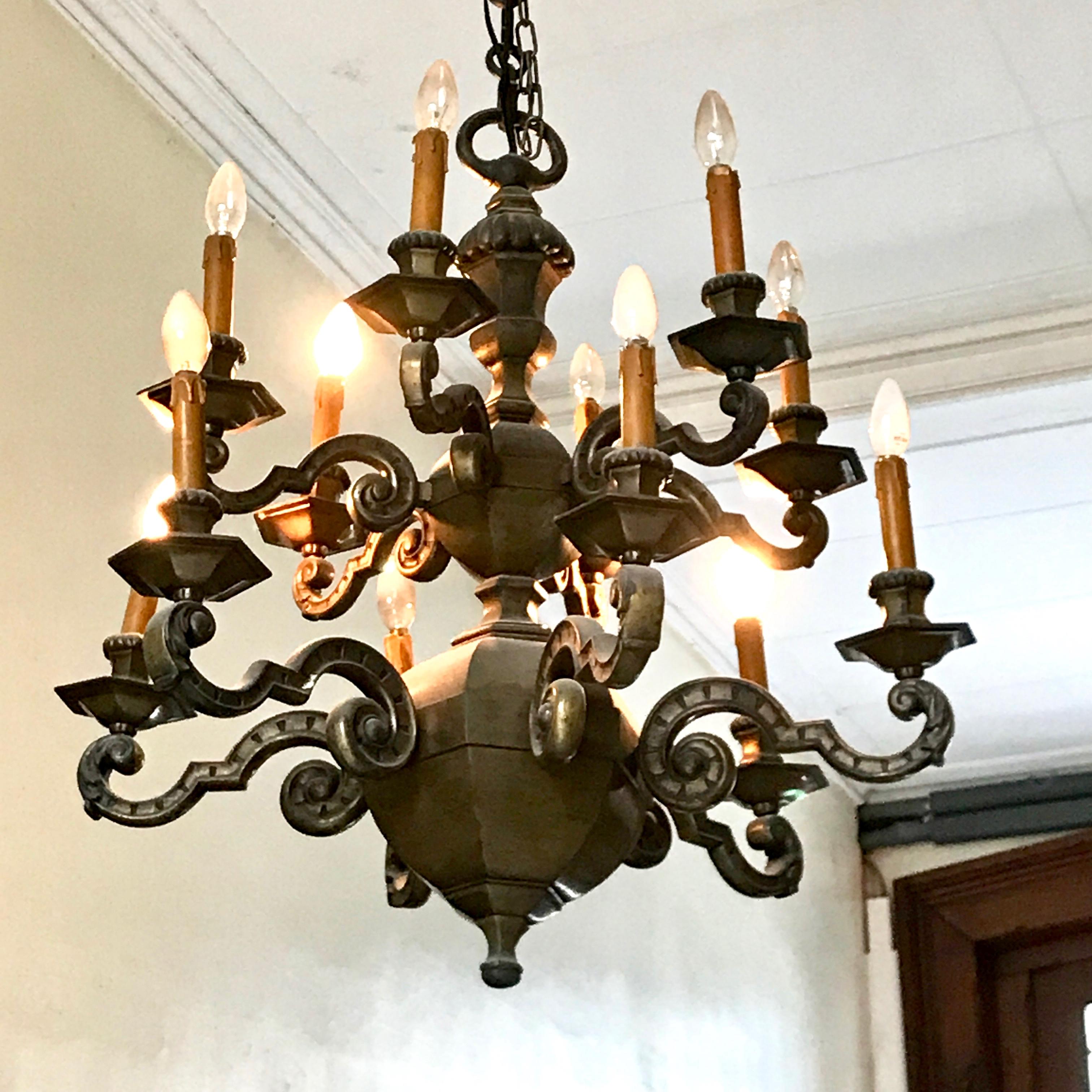 French circa 1900 two-tier cast bronze chandelier with 12 arms. Beautiful sculptural shape consisting of a large hexagonal ball on the bottom, a smaller hexagonal ball above and topped with an urn. Fine attention to the design details such as the