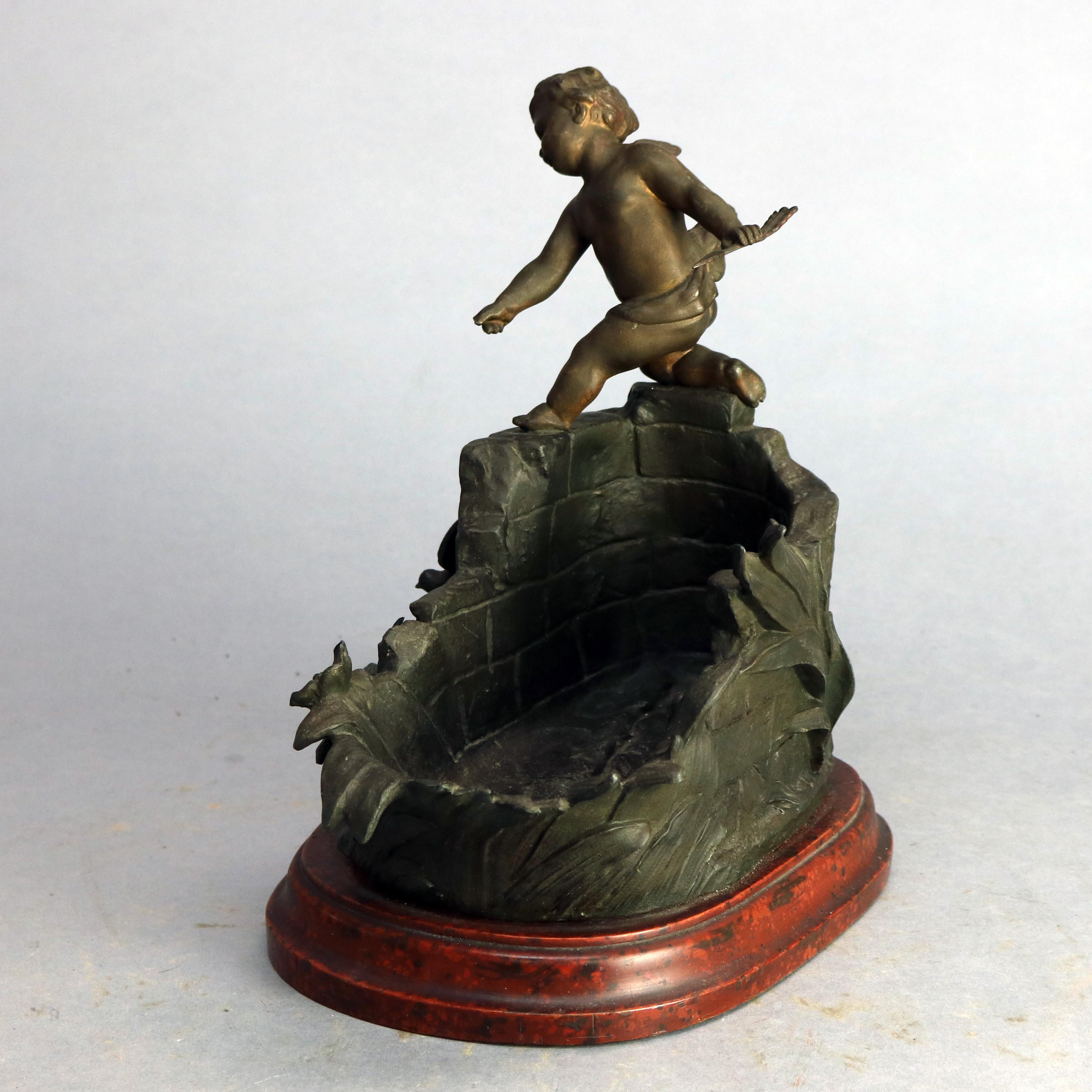 Antique French bronzed cast metal sculpture of cherub over bowl in the form of architectural ruins with foliate elements and bird seated on stepped faux marble painted wood base, title plate reads 